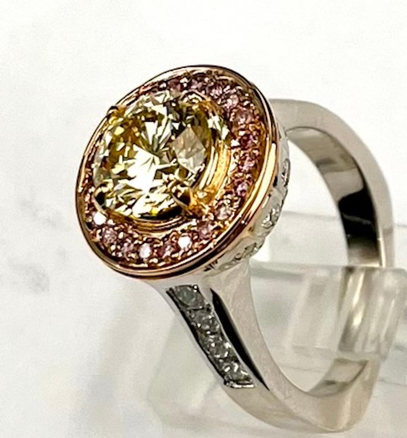 This custom platinum ring features a 1.89Ct Natural Fancy Yellow Diamond that is also a VS1 in clarity and is surrounded in a halo of natural pink diamonds. Round diamonds that are a Natural Fancy Yellow Color are quite rare, especially in this size