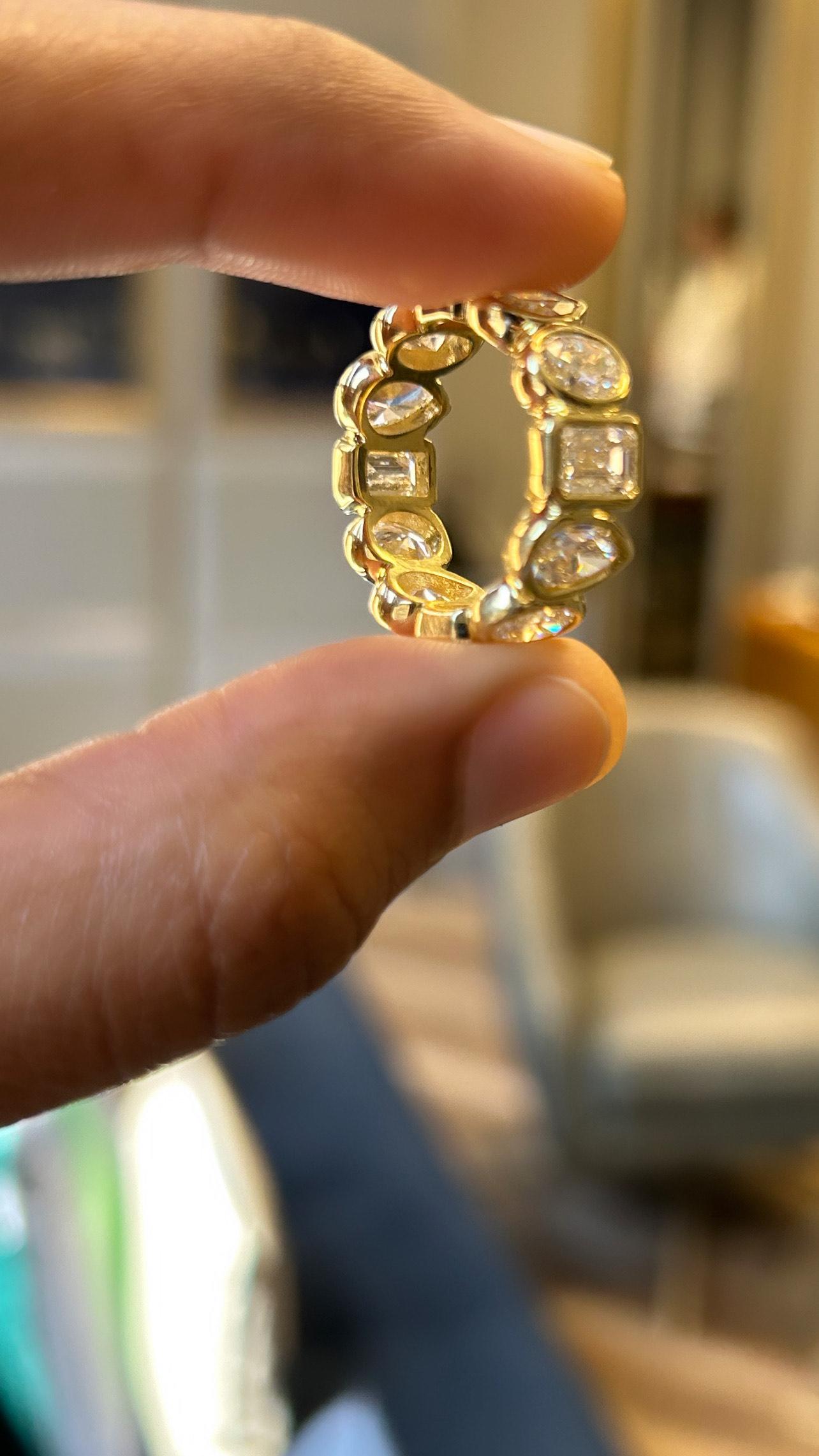 This is a stunning GIA Certified 18K yellow gold (YG) diamond eternity band featuring a variety of diamond shapes. The ring includes:

The band showcases multiple diamonds in different shapes, including pear, emerald, and oval cuts. Total diamonds