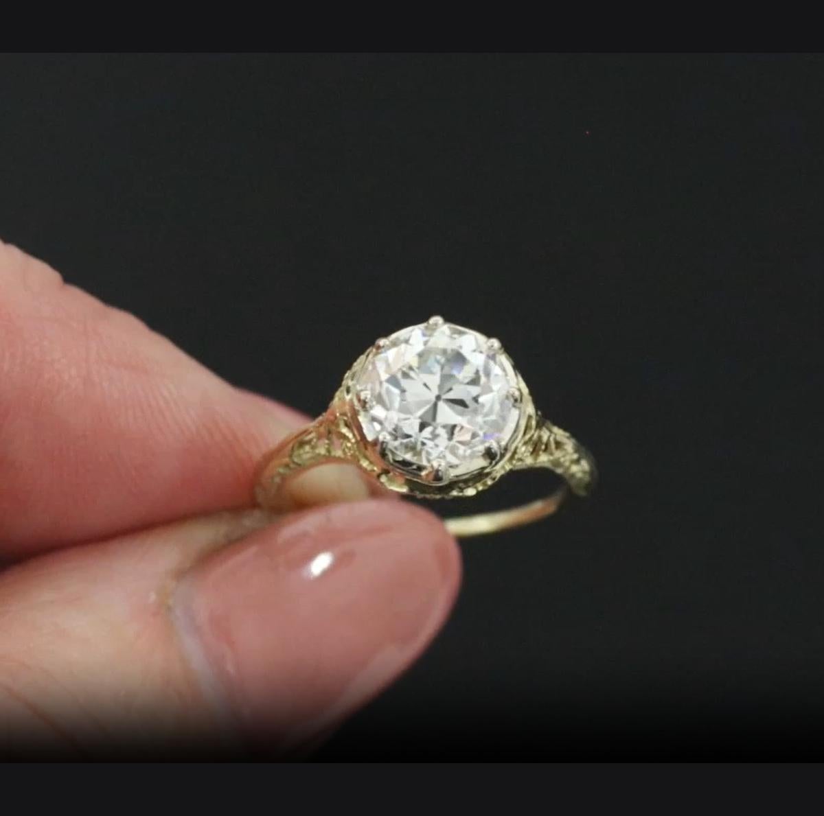This exquisite vintage engagement ring showcases a rare and exceptional 1.90 carat old European cut diamond, GIA certified with E color and VS2 clarity — remarkably bright, white, and eye-clean. The center diamond is set in an intricately detailed