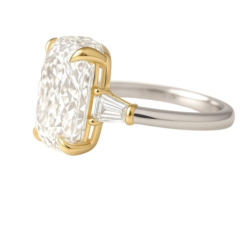 This exquisite three-stone engagement ring centers a rare GIA-certified 2 carat Old Mine Brilliant cut diamond, beautifully shaped with softly rounded corners and broad facets that radiate antique charm and brilliance. The cushion-shaped diamond is