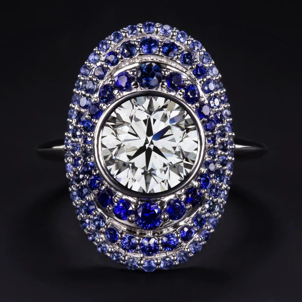 An exquisite diamond and sapphire ring offers a striking statement look with a sea of rich blue sapphires. The ring features a large 2.01 carat GIA certified diamond encircled by three elegantly graduated and gracefully domed halos of round cut
