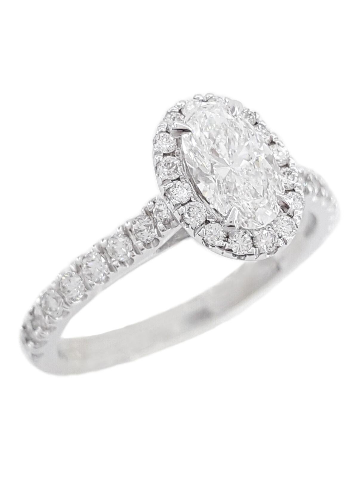 This stunning 2 carat F color VS clarity oval brilliant cut diamond ring in 18K white gold features a captivating halo setting adorned with pavé diamonds, exuding timeless elegance and sophistication. 
At the heart of this exquisite ring is a