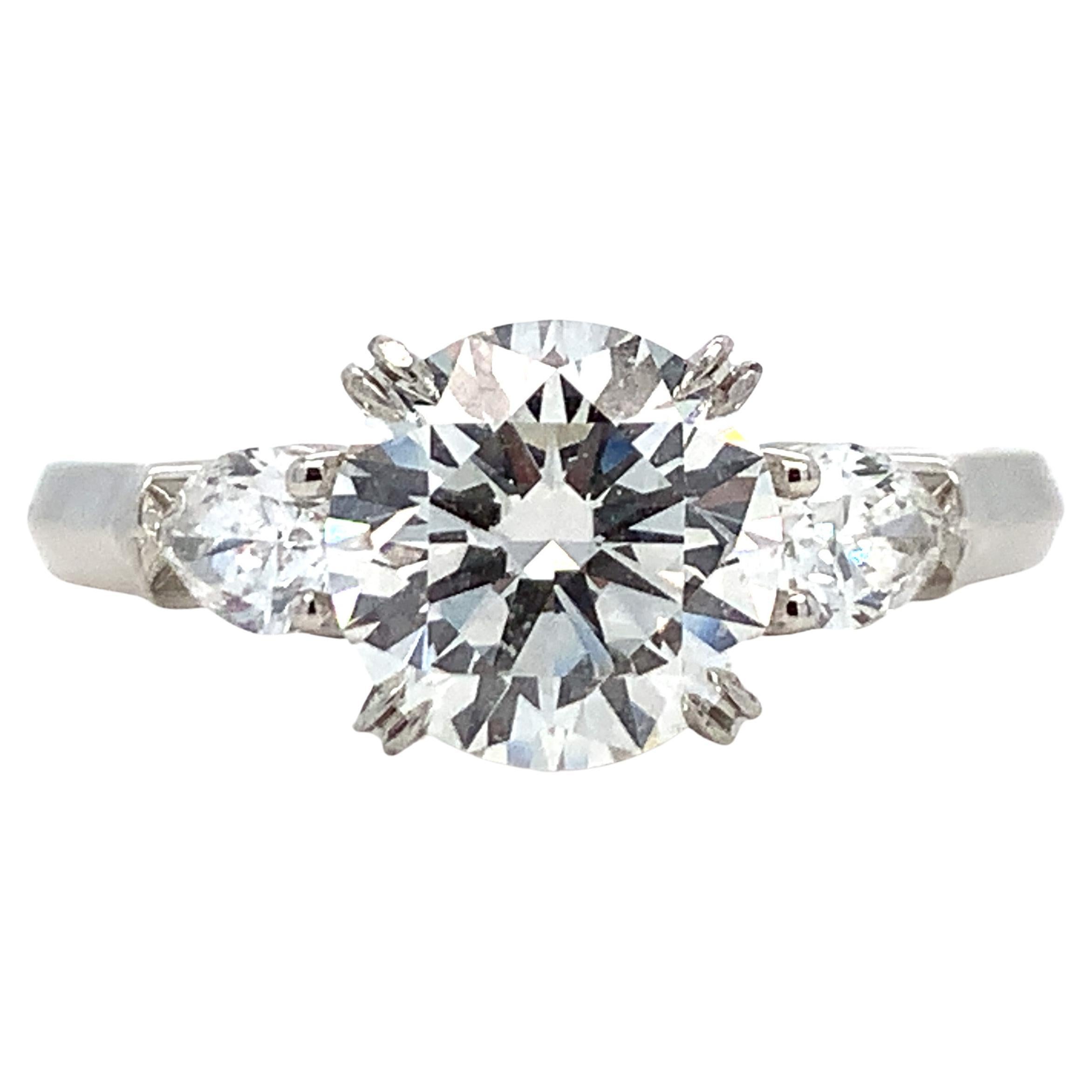 This three stone Harry Winston diamond engagement ring is crafted from platinum. It features three natural diamonds. The center diamond is GIA certified. It's 1.60 carat, color F, and clarity VS1. Each pear diamond is approximately 0.20 Ct, clarity