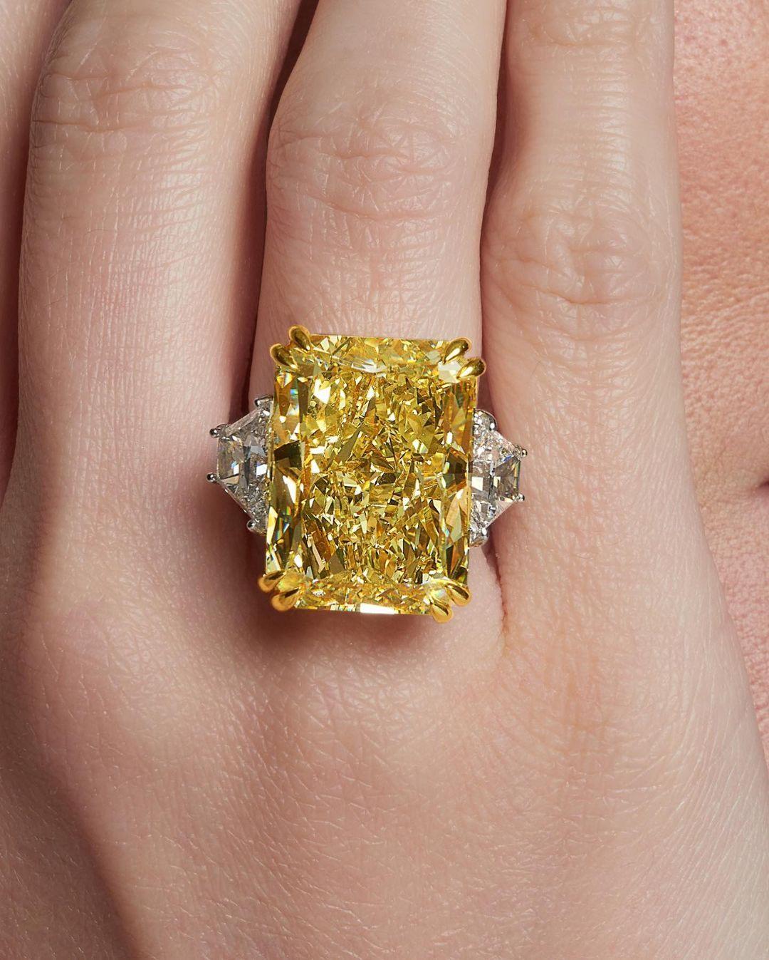 This stunning engagement ring boasts a magnificent centerpiece: a GIA certified 15.80 carat fancy yellow diamond solitaire. The diamond's fancy yellow color grade radiates a captivating and vibrant hue, imbuing the ring with a sense of unparalleled