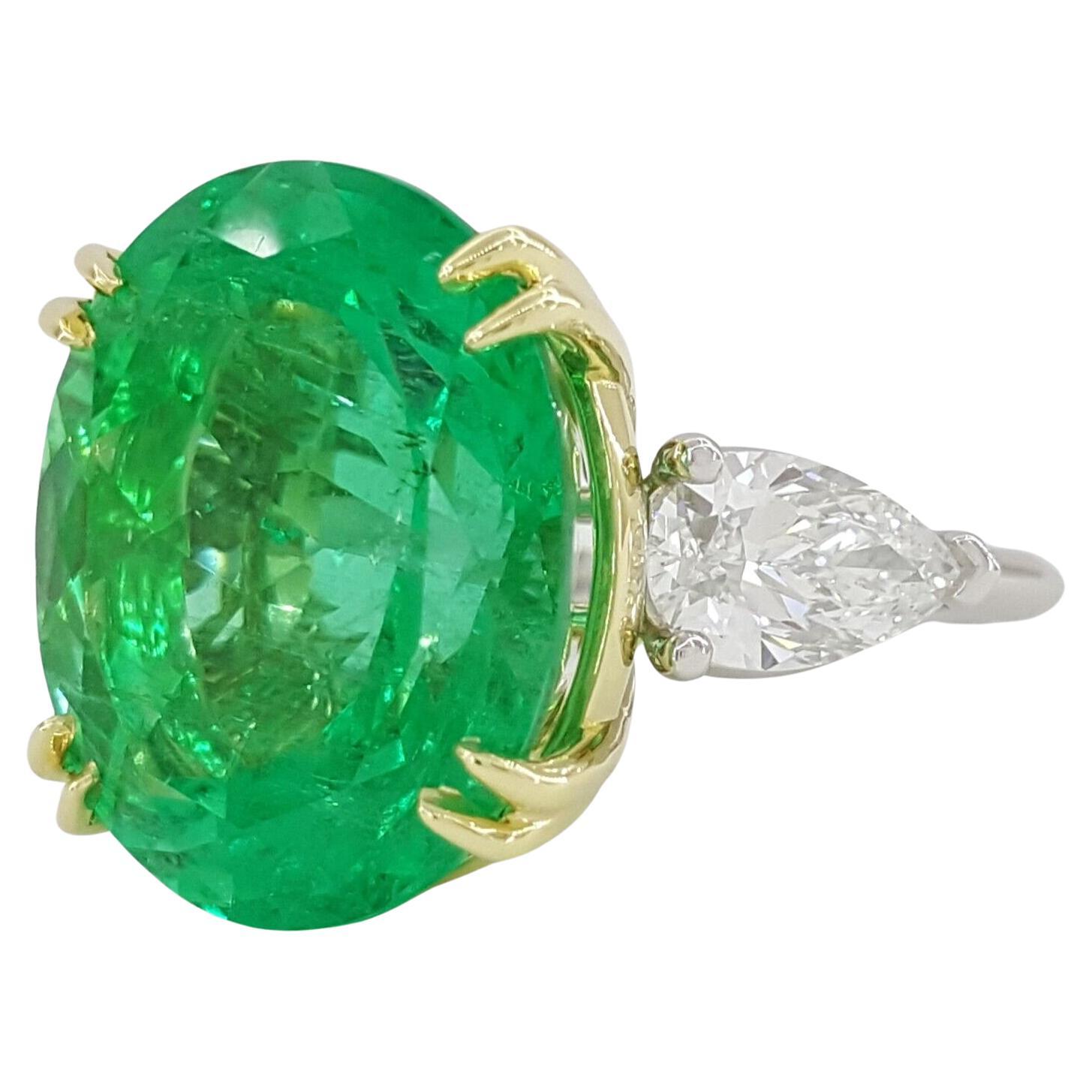 An investment grade Oval Cut Natural Colombian Green Emerald & Pear Cut Diamond Engagement Ring. 

The ring weighs 16.9 grams, size 6.5. The center stone is a very lively Natural Oval Cut Green Emerald weighing 20.19 ct, Green in color. The