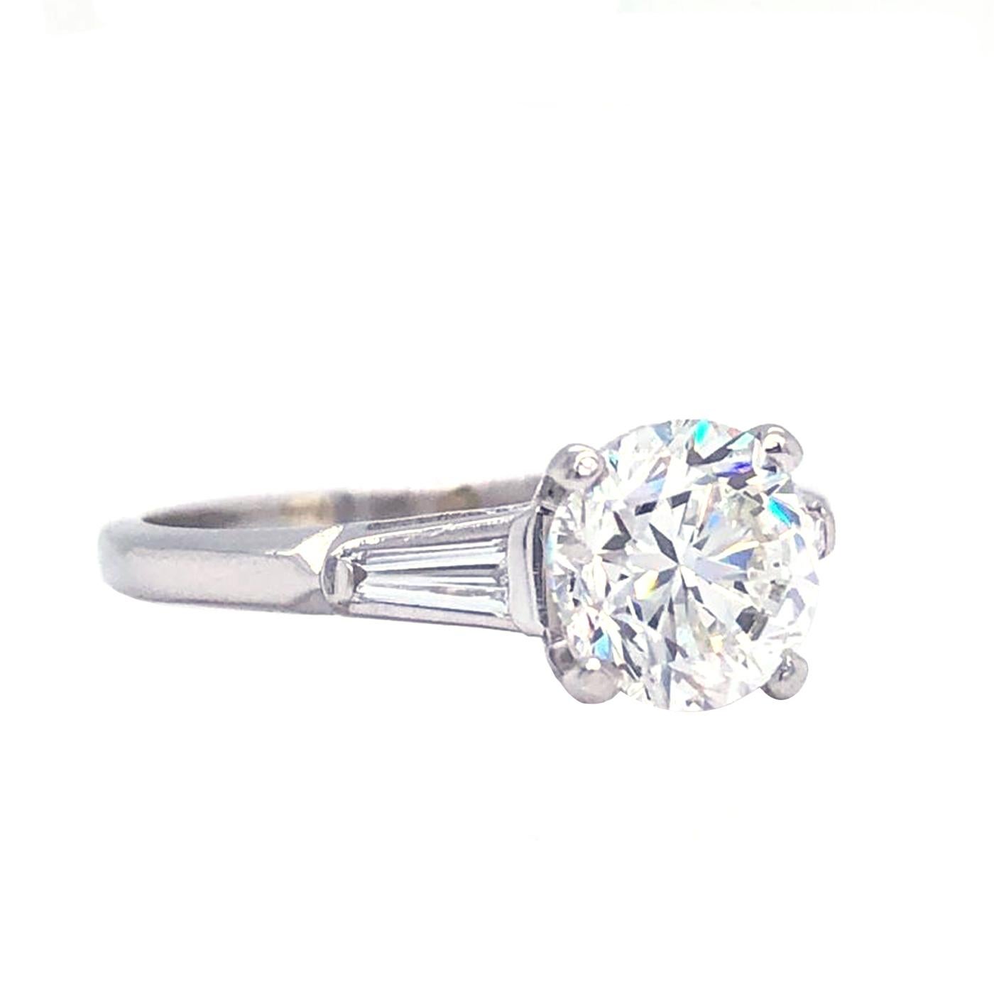 Classic Platinum Diamond ring 2.00 Carat center Round Brilliant Certified by Gia as I - Color, Si2  Clarity, and accented by two tapered baguette-cut diamonds, Totaling 0.35 carat H color, VS1 - Clarity, The ring weighs 3.2 grams, and is currently