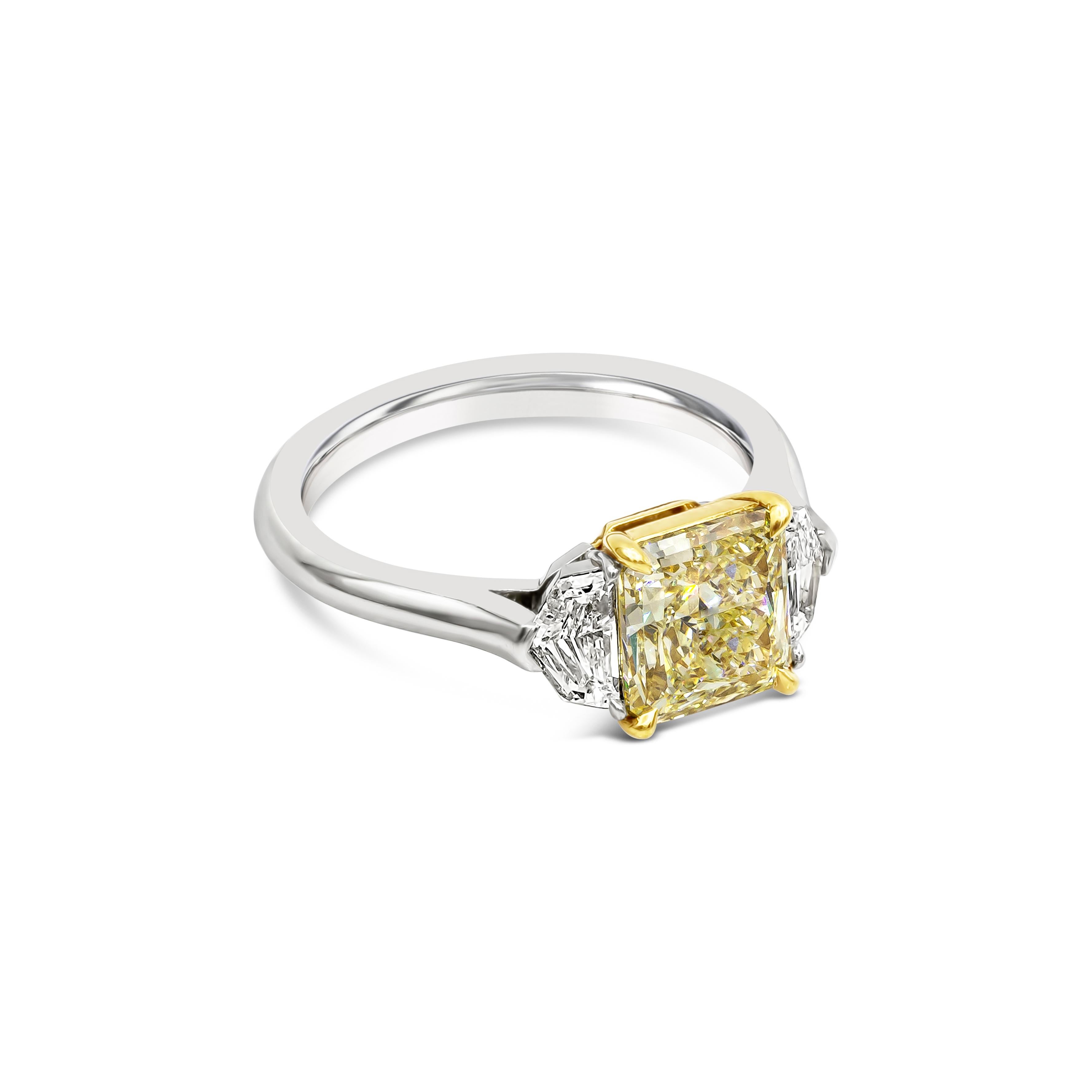 A gorgeous 2.01 carat radiant cut yellow diamond that GIA certified as Y-Z color, VS1 clarity, takes center stage in this three stone engagement ring. Flanking the center diamond are two shield cut diamonds weighing 0.47 carats total. Set in a 18k