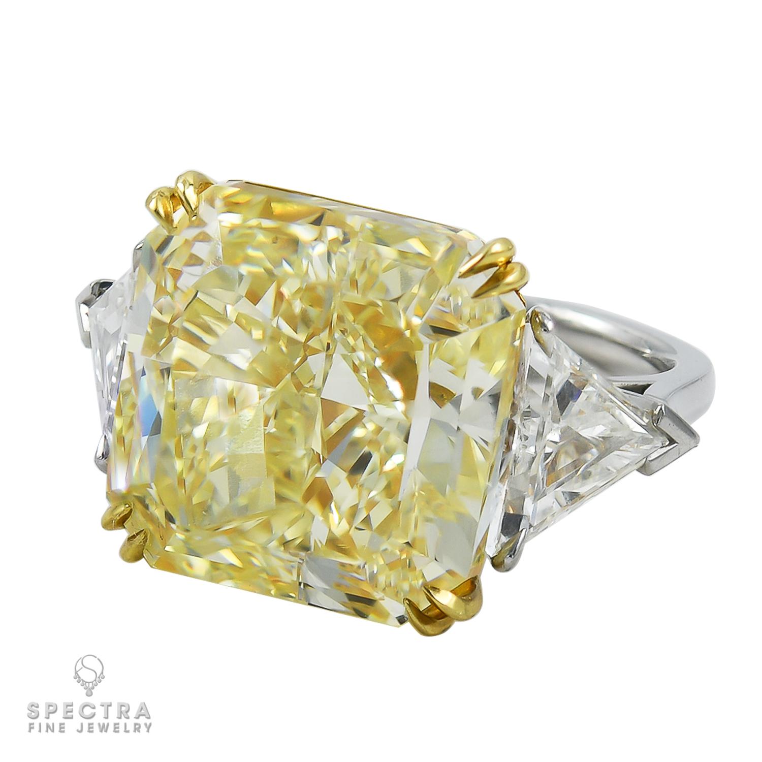 A beautiful cocktail or engagement ring featuring a canary (fancy yellow) diamond weighing 20.11 carats, accented with two white triangular diamonds on both sides weighing 2.23 carats total, by Spectra Fine Jewelry. 
The yellow diamond is