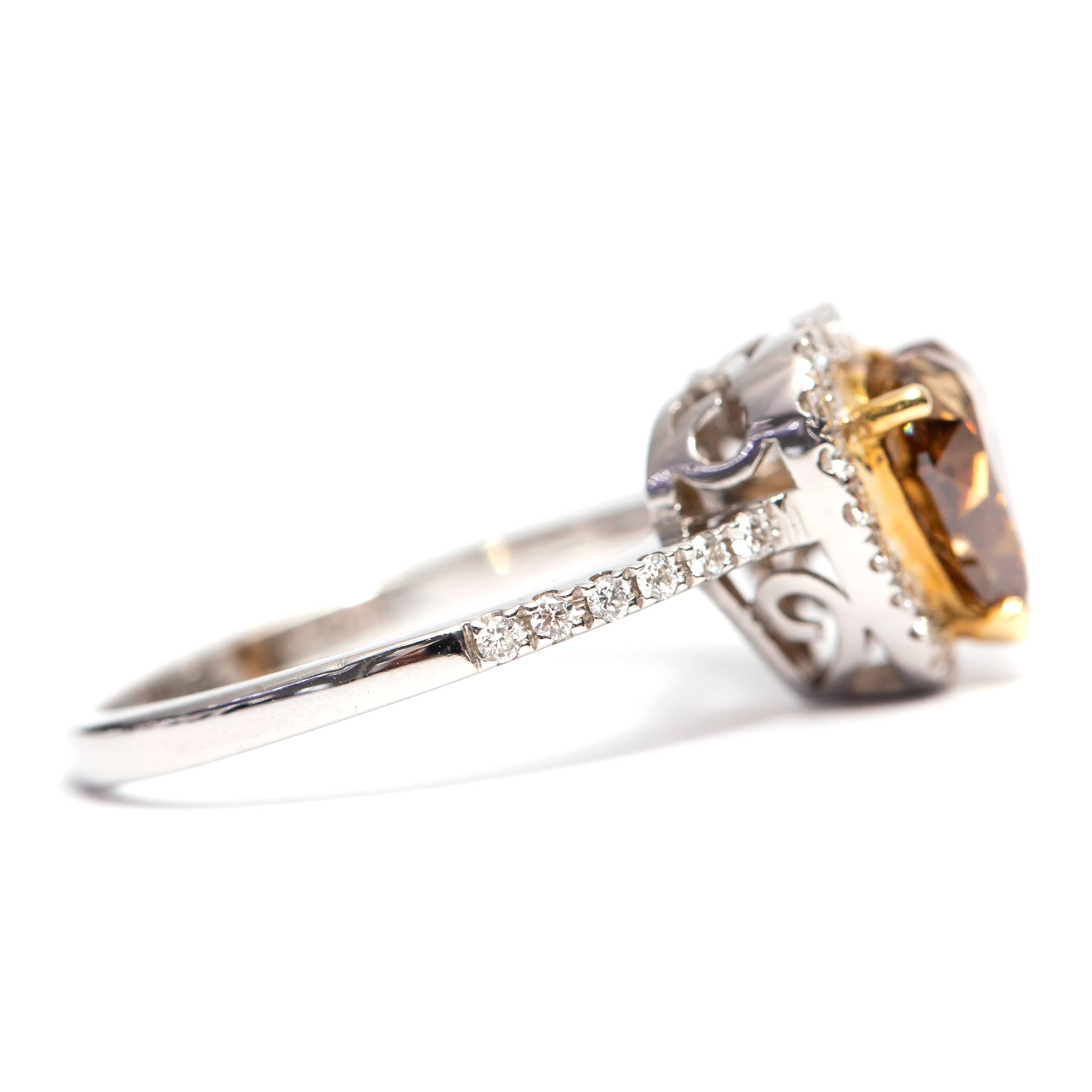 This Stunning GIA Certified 2.02 Carat Natural Fancy Yellow-Brown Heart Brilliant Diamond set in the center of the Halo featuring 0.30 Carat of G-VS Round Brilliant Diamonds around the Halo and shoulders of the ring giving this beautiful Halo