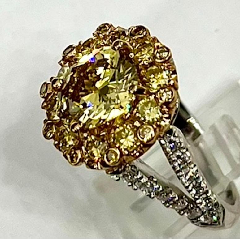 This ring has as a focal point a 2.02Ct Cushion Cut Natural Fancy Deep Yellow Diamond. The color on this diamond is very rich and saturated. It is surrounded by an artistic halo of Natural Round Yellow Diamonds set in prongs and in besels. The split