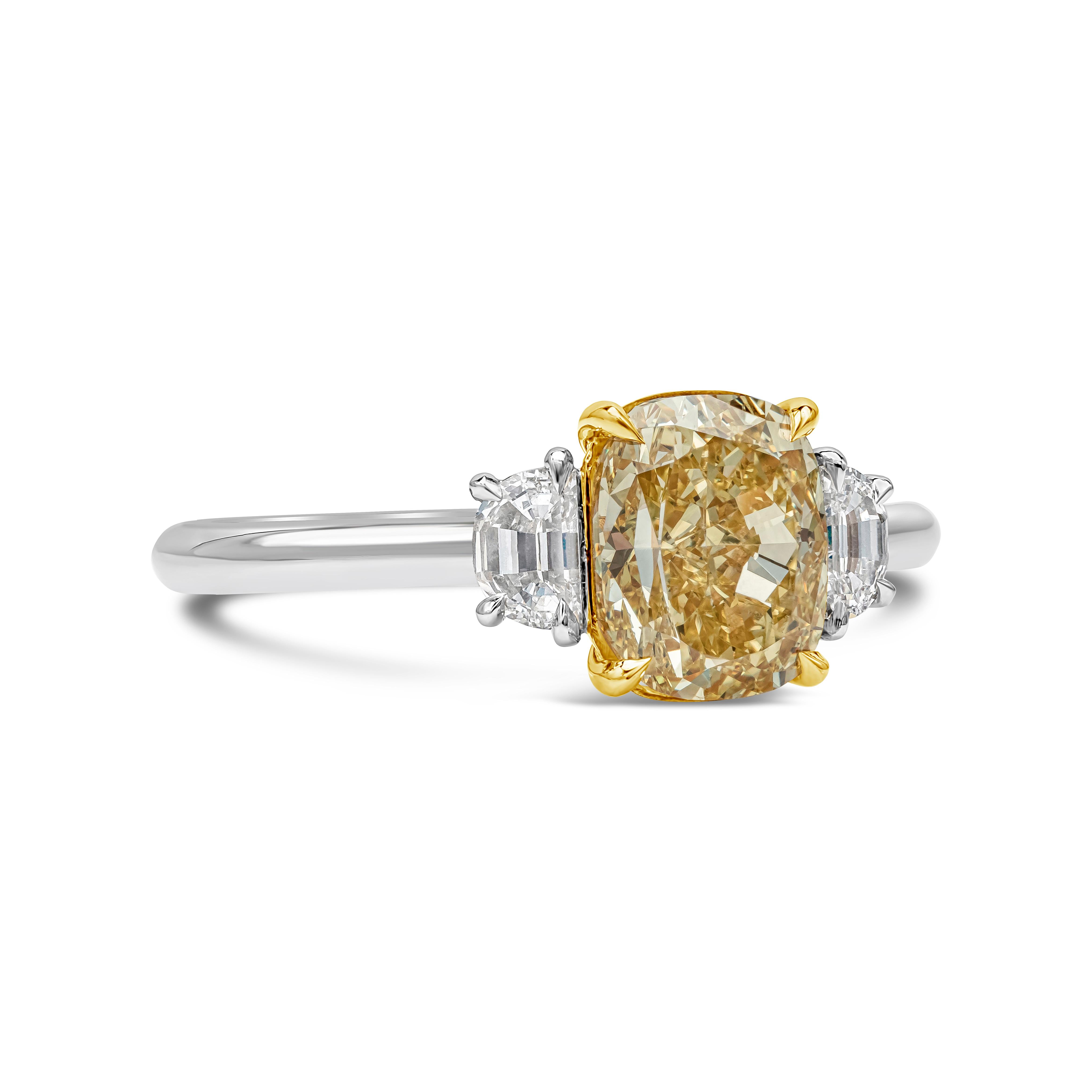Features a 2.03 carats cushion cut yellow diamond certified by GIA as fancy Intense Yellow color, VS2 in clarity, set in a classic four prong basket setting. Flanking the center stone are two step-cut half moon diamonds on each side, set in a