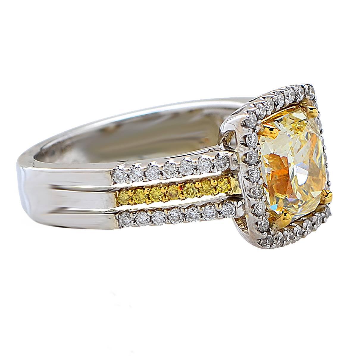 Dazzling ring crafted in 18 karat yellow and white gold, showcasing a GIA Certified natural light yellow radiant cut diamond weighing 2.03 carats, VVS1 clarity, accented by 68 round brilliant cut diamonds weighing approximately .50 carats total.