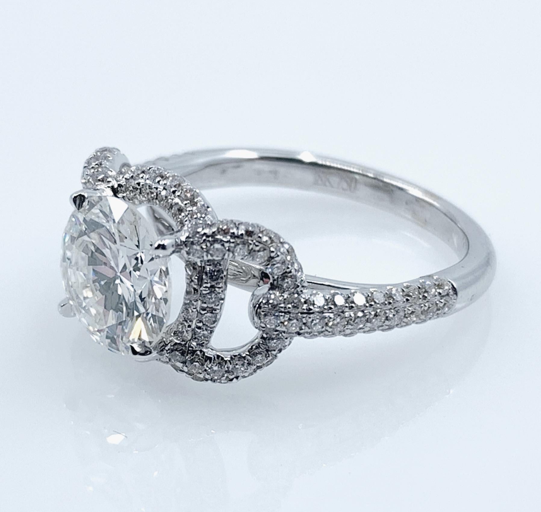 A gorgeous engagement ring or solitaire, featuring a large round brilliant-cut diamond prong-set and slightly elevated over a double halo of good-quality melee white diamonds.  Lapping over the halos at the shoulders are open 
