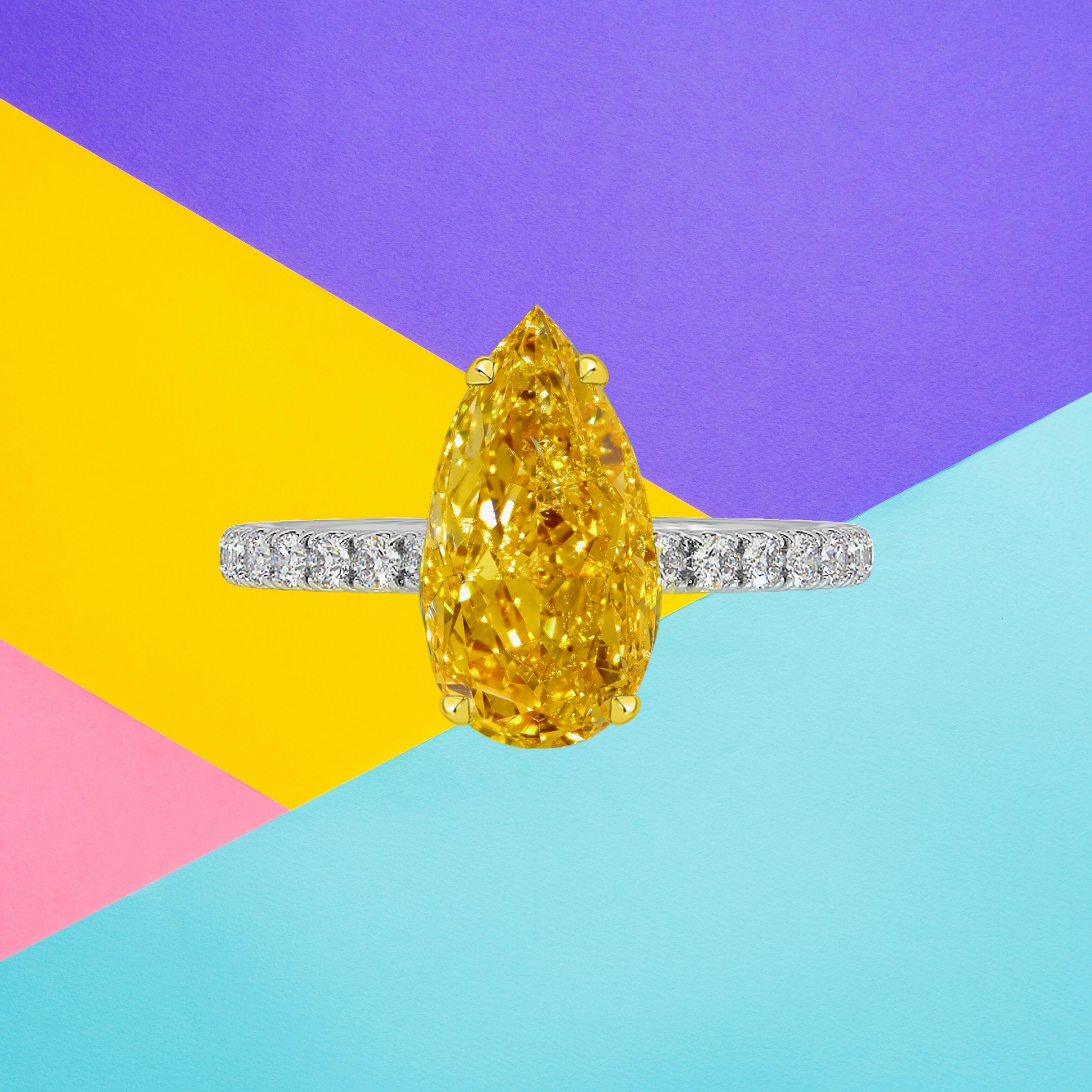This pear shape diamond weighs 2.08 carat and is certified 'Fancy Vivid Yellow-Orange' color by the Gemmological Institute of America. The GIA has also assigned an I1 clarity grade to the stone. The diamond has been inscribed with the certificate