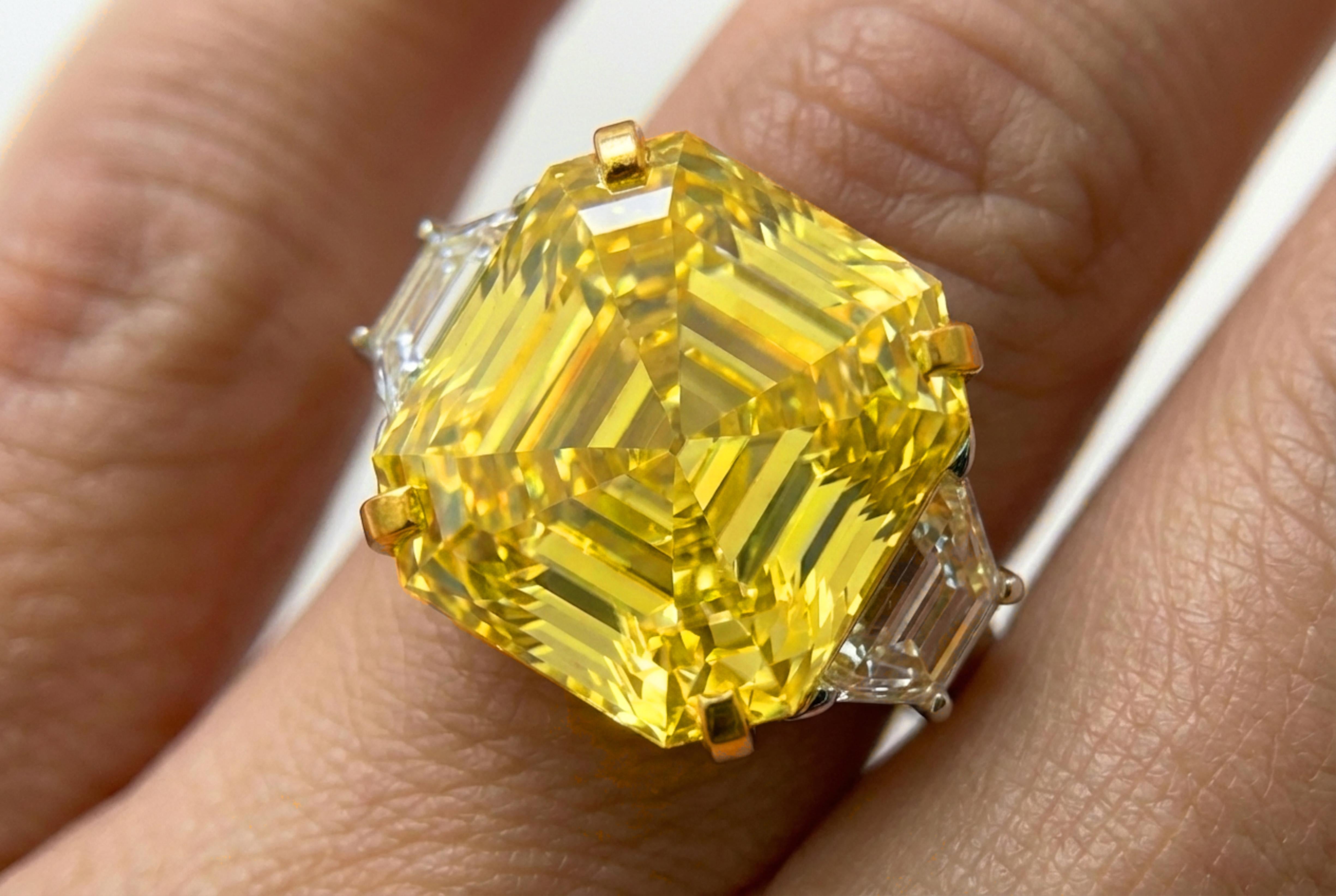 Présentation d'un extraordinaire diamant Fancy Yellow de 21,84 carats, de qualité investissement, serti de manière experte dans une monture sur mesure en or jaune 18 carats et en platine. Ce rare diamant carré de taille émeraude séduit par sa taille