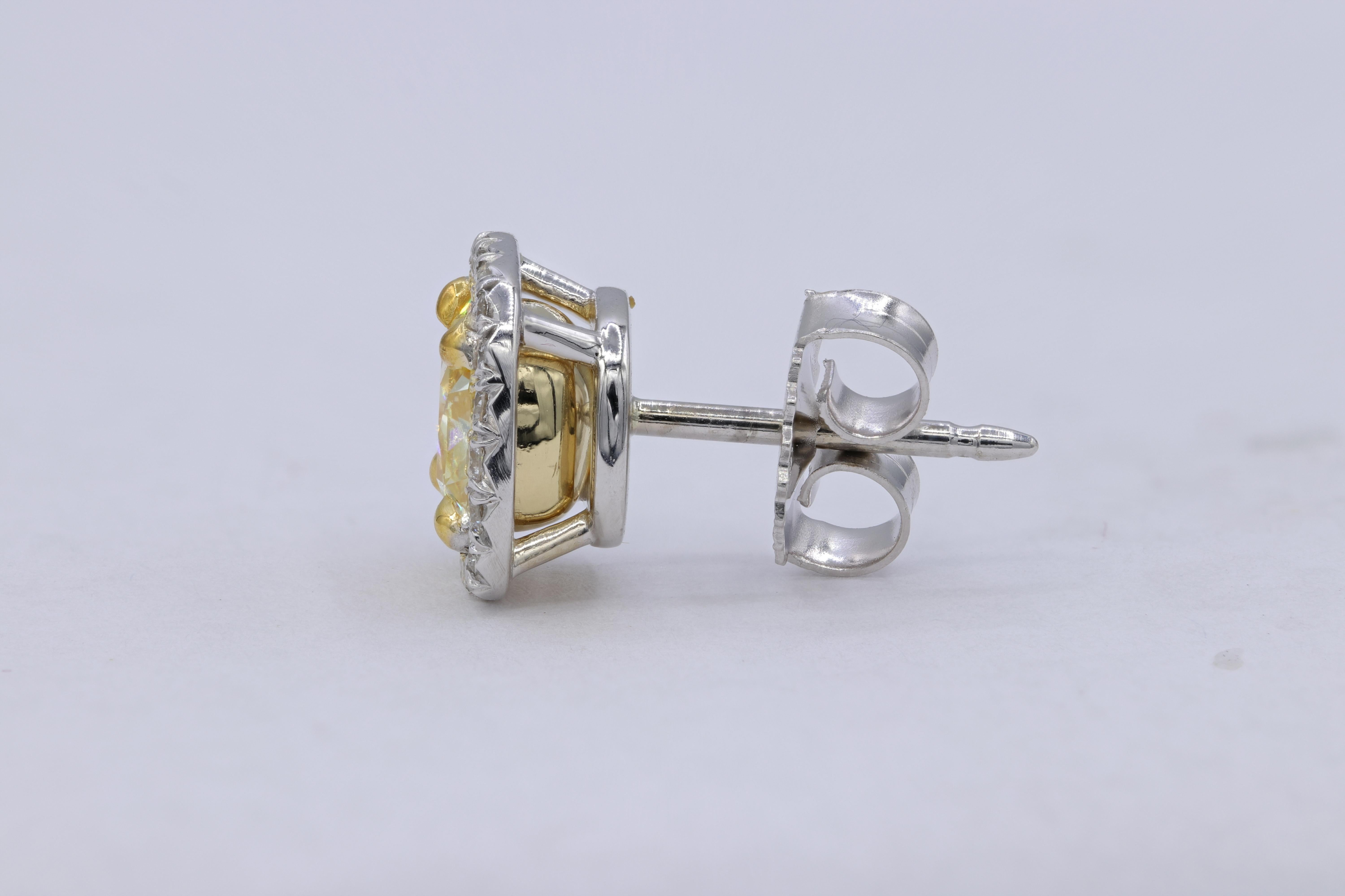 18K White gold Fancy Yellow diamond stud earrings with two GIA Certified Cushion Cut Diamonds. 
- Center diamonds totaling 2.10 Carats Fancy  Yellow Cushion Cut Diamonds, VVS1 AND VS2 in Clarity 
- GIA#1192256937; 1192264192
- Diamonds around