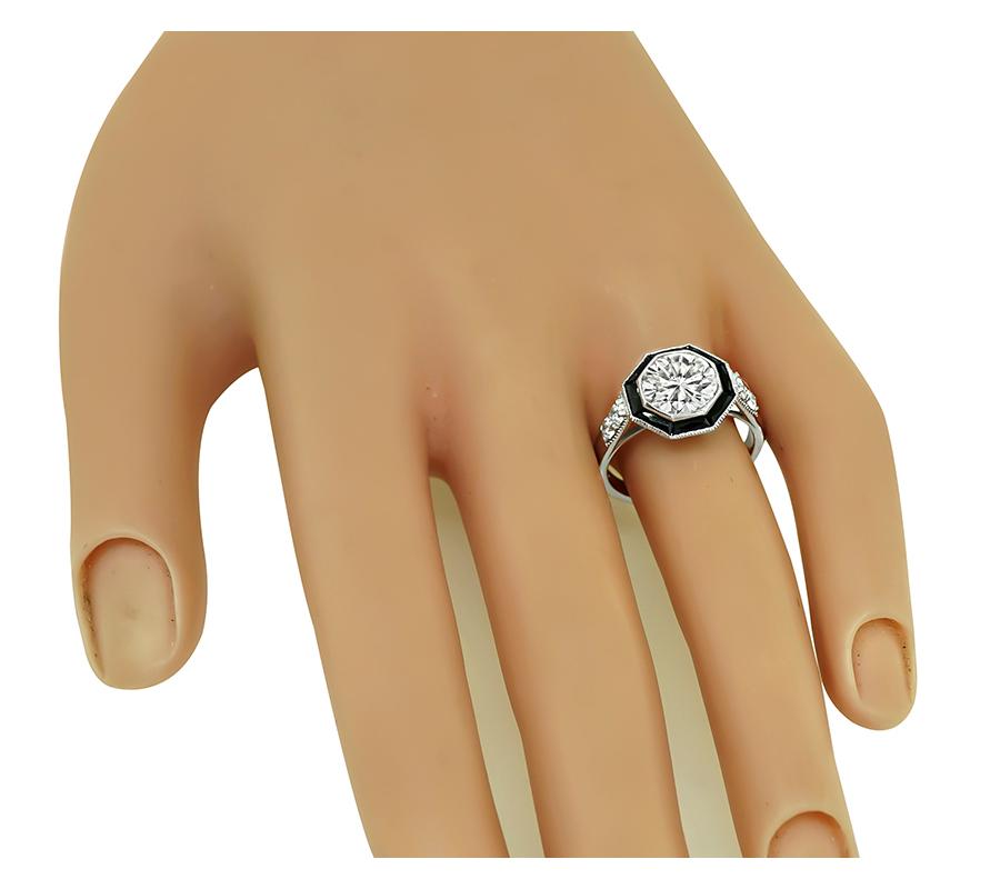 This is a stunning platinum engagement ring. The ring is centered with sparkling GIA certified round cut diamond that weighs 2.10ct. The color of the diamond is J with SI1 clarity. The center diamond is accentuated by lovely baguette cut onyx and