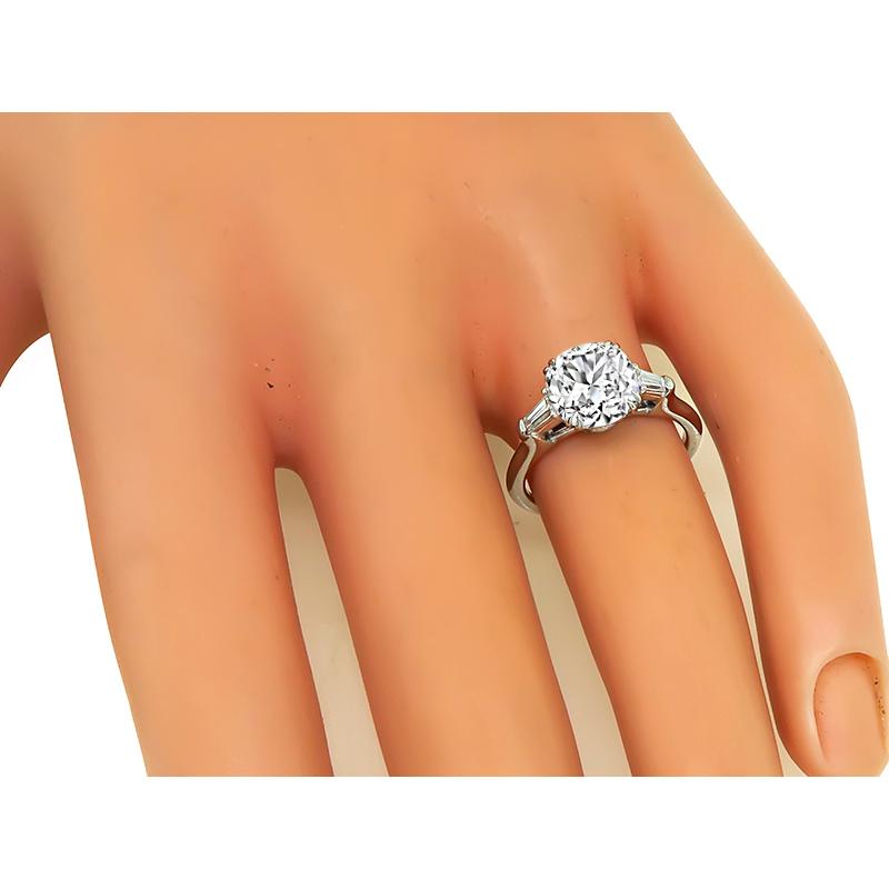 This is a charming platinum engagement ring. The ring is centered with a sparkling GIA certified cushion cut diamond that weighs 2.18ct. The color of the diamond is J with VS2 clarity. The center diamond is accentuated by dazzling baguette cut