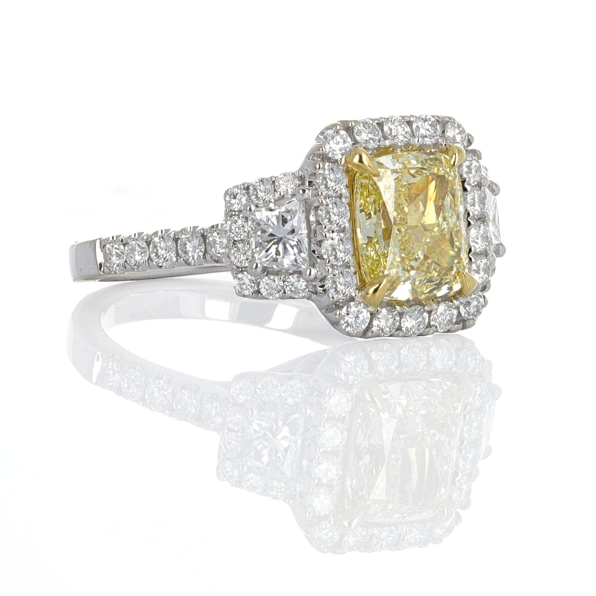 Three stone, GIA certified, Fancy Light Yellow cushion cut diamond ring. The center stone weighs 2.20 carats. The side stones, including the pave, weigh 1.14 carats. GIA describes the center stone as a natural cushion modified brilliant cut diamond.