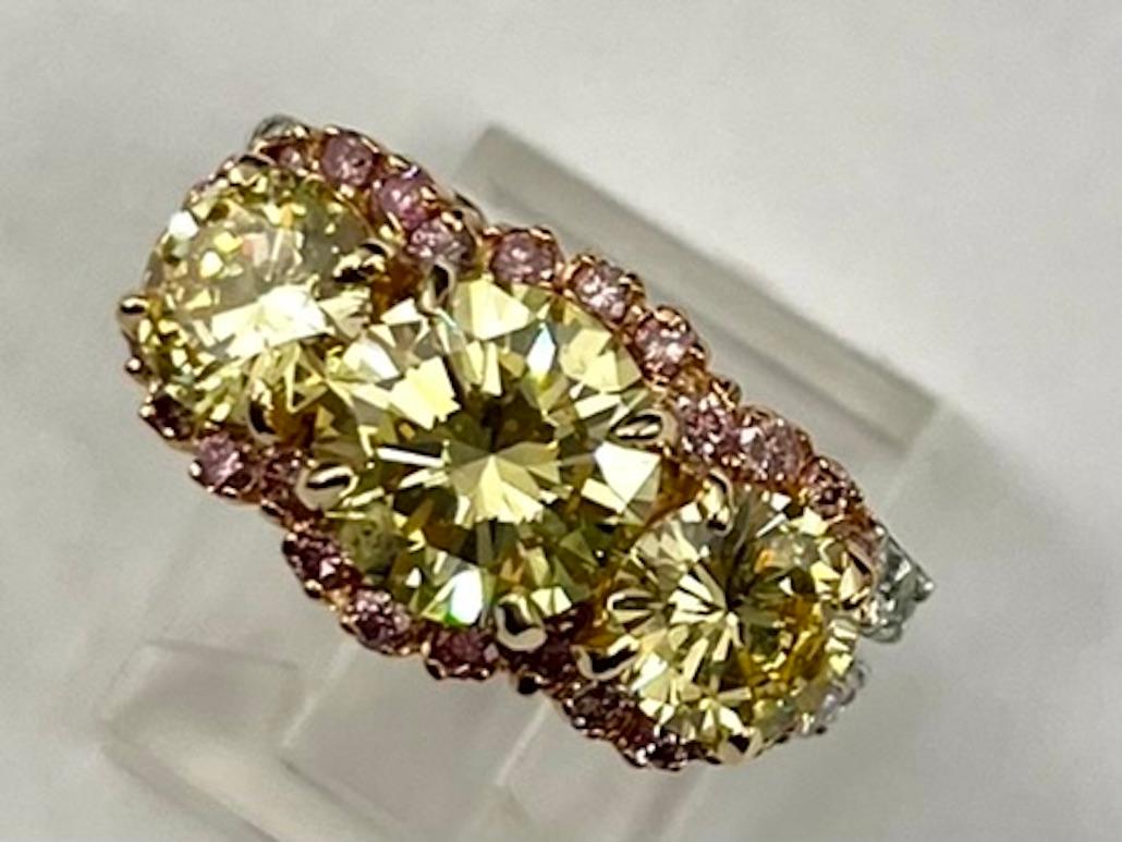 This is a magnificent and one of a kind ring. Yellow diamonds are not often cut to a round shape because a round shape diamond disperses more light, thereby reducing the effect of the yellow color. This ring has not one, but three round diamonds
