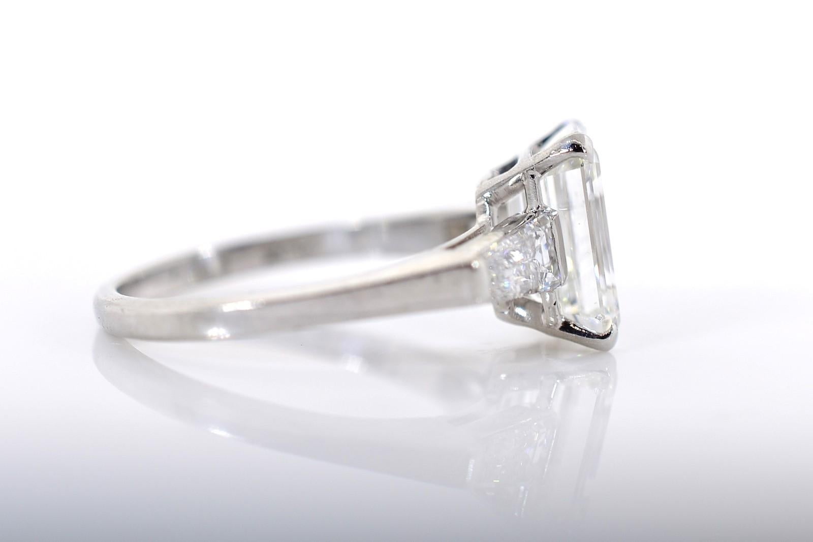 A sparkling 2.23 carat Emerald cut Diamond highlights this classic 1950's platinum beauty.  Two brilliant tapered Baguette Diamonds lead our eyes to the G.I.A. certified (2205876771) F color - VS2 clarity centerpiece.  The low profile ring setting