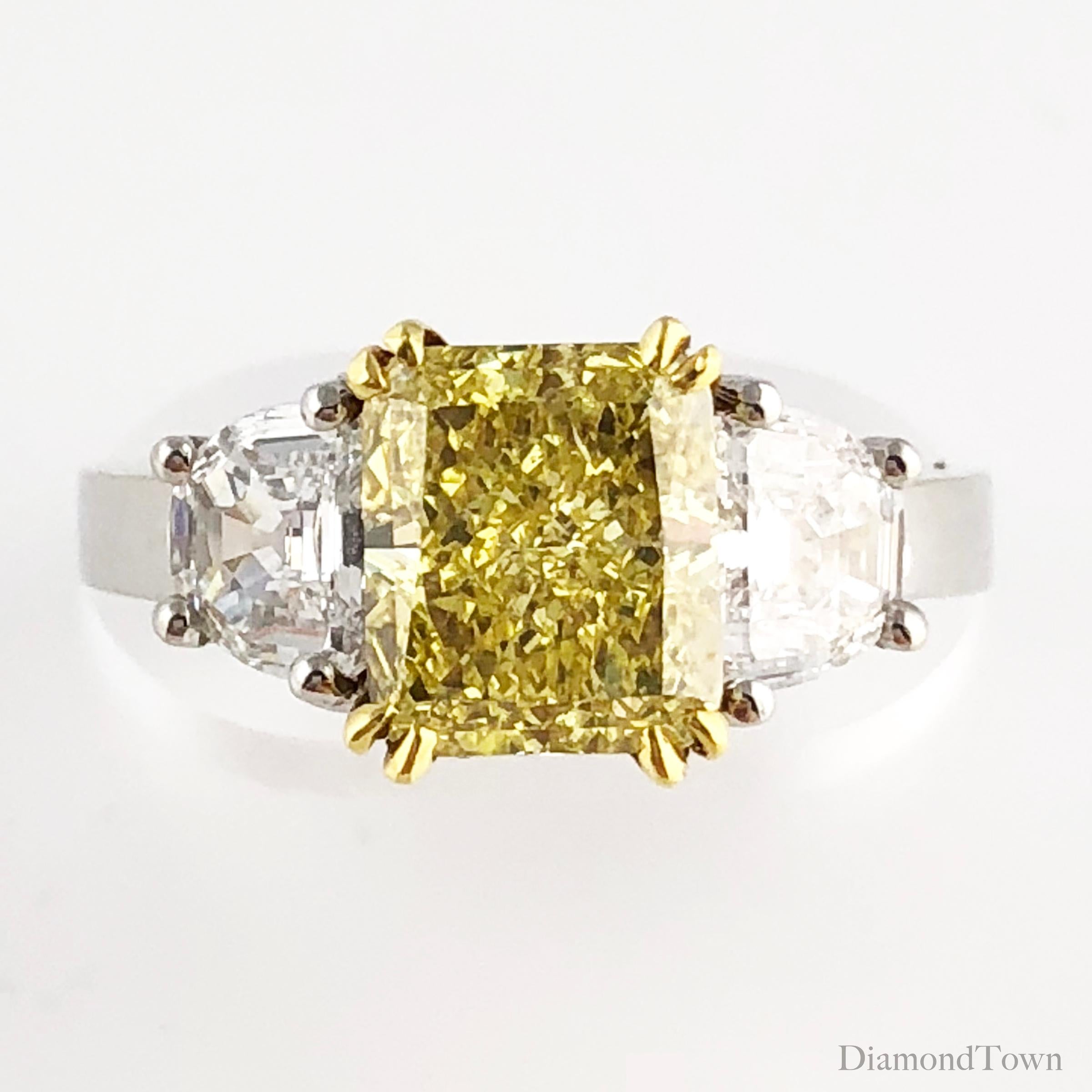 (DiamondTown) This gorgeous handcrafted ring features a 2.25 carat GIA certified radiant cut Natural Fancy Intense Yellow diamond center, flanked by two half-moon diamonds, bringing the total diamond weight to 3.10 carats. The ring is set in
