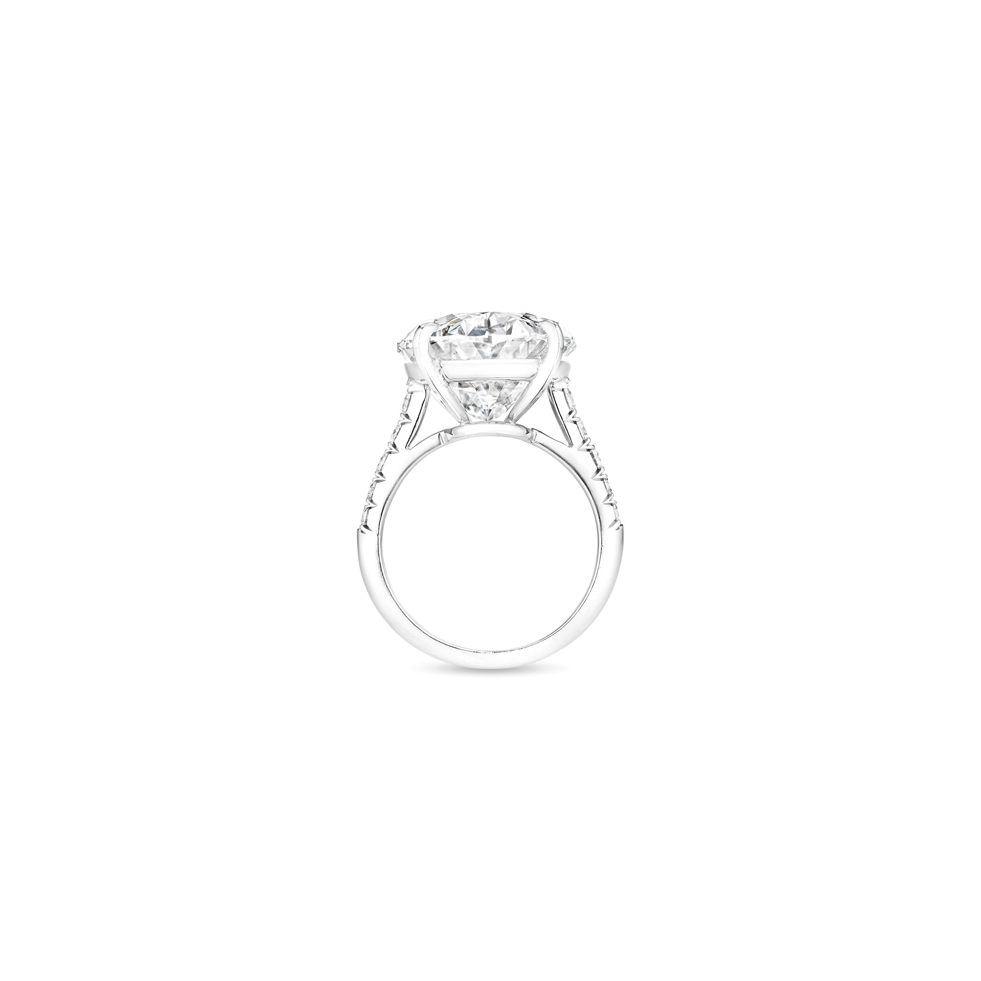 23 Carat Oval Cut Diamond three-stone engagement ring is an exquisite piece crafted in platinum. The centerpiece is a stunning 23 ct natural oval brilliant cut diamond that boasts an i color grade and vvs2 clarity, indicating exceptional quality.

