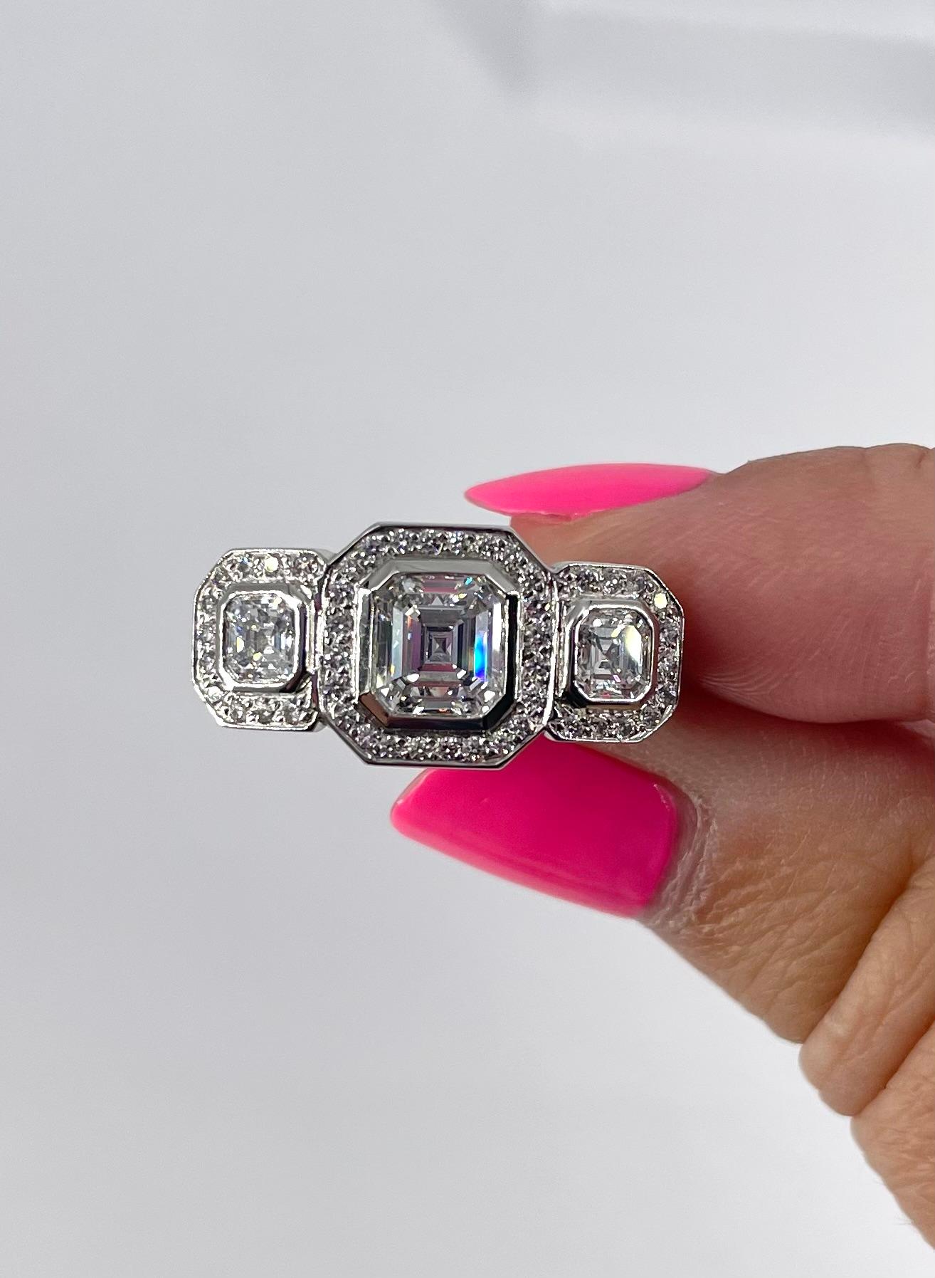 Questo impressionante anello con tre pietre è perfetto per chi vuole farsi notare! L'anello presenta tre diamanti taglio Asscher: il centrale è di 1,10 carati e certificato GIA con colore F e purezza SI2. I diamanti ai lati pesano in totale 1,06