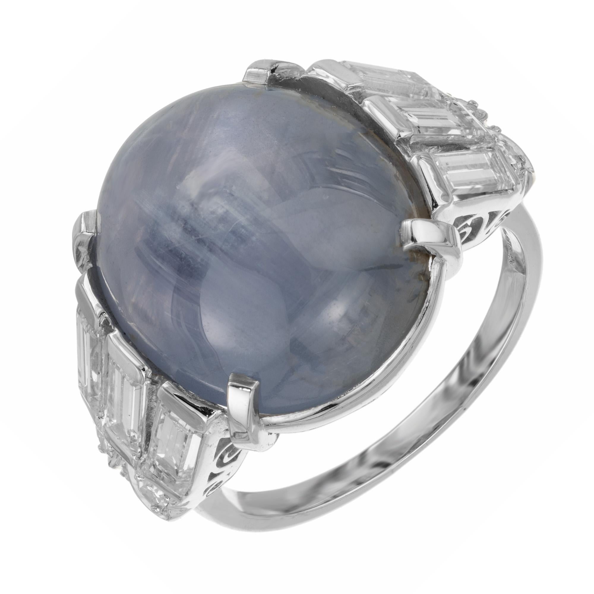 Il nostro anello con zaffiro ovale e diamanti Art Deco da 23,19 ct. certificato GIA è uno squisito capolavoro che trasforma l'eleganza in arte da indossare. Il fascino enigmatico dello zaffiro cabochon a stella, che brilla come uno scintillante