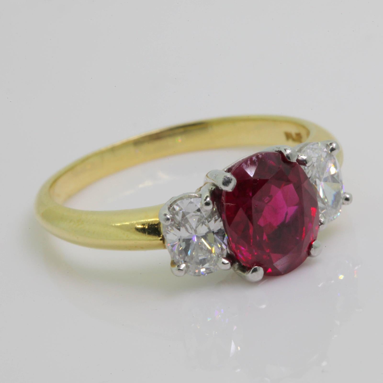 A vibrant red 2.41 carat oval cut Burma Ruby and 18KT yellow gold ring; accompanied by G.I.A. certificate stating the Ruby is heated and of Burma origin.  This  luscious  Ruby is flanked by two oval  Brilliant cut Diamonds, both weighing 0.80 carat