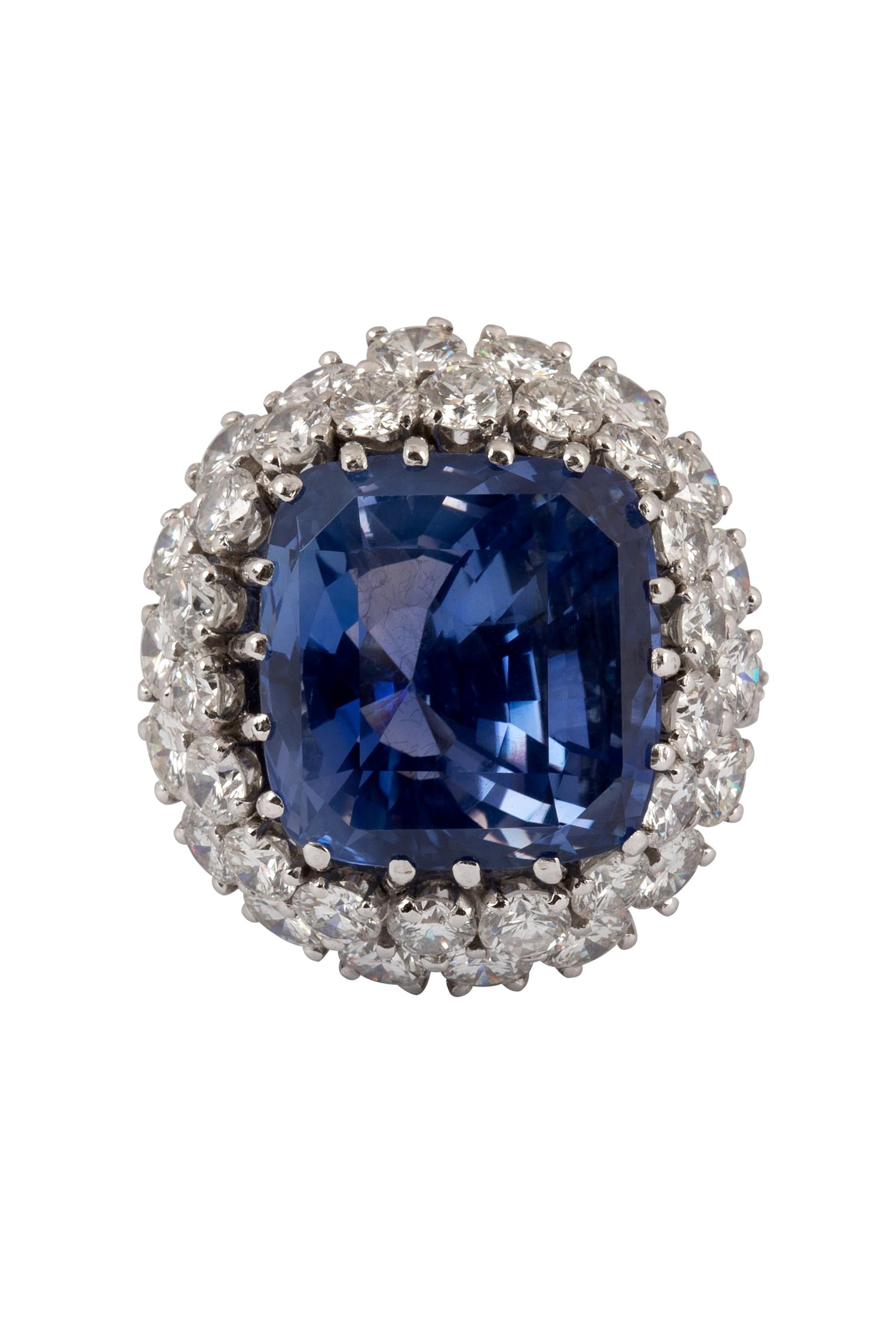 An exceptionally rare 24.18 carat color change cushion cut sapphire radiates from the center of this luxurious and lavish ring. Shifting from a striking bluish violet in daylight to a rich purple in incandescent light, the sapphire is artfully
