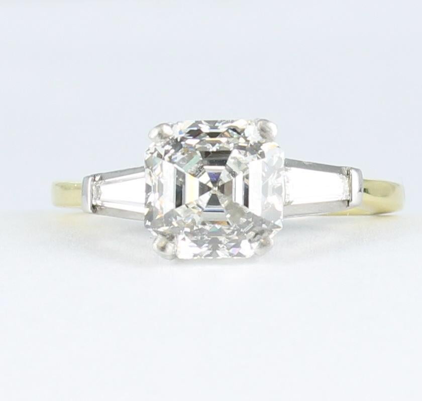 An amazing 2.43 carat Asscher-cut diamond, GIA certified VS 1 clarity, F color, is complemented by a lovely baguette diamond on either side in this fabulous engagement ring. The diamonds are set in Platinum and the shank is 18 karat yellow gold.