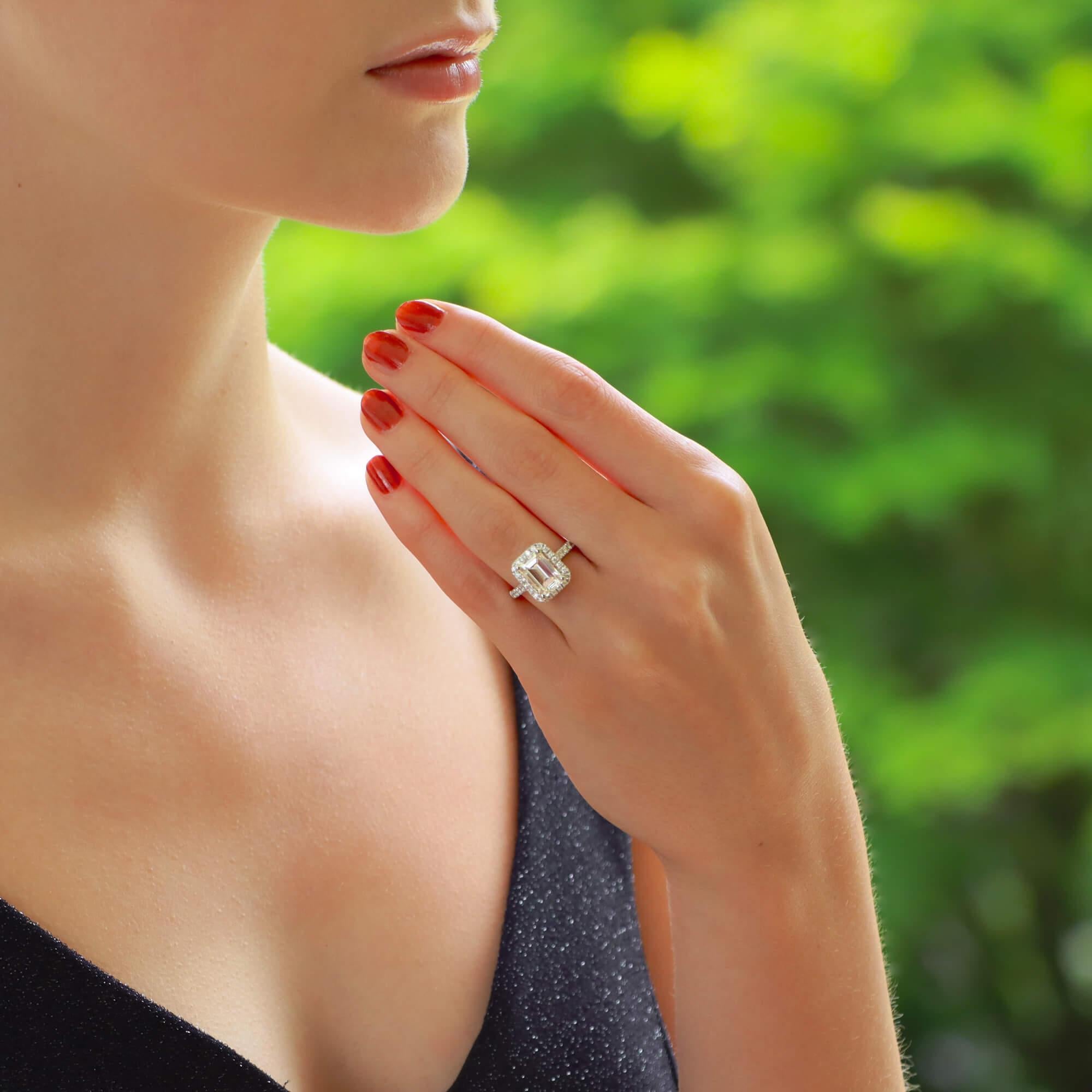 A beautiful emerald cut diamond halo engagement ring set in 18k white gold.

The ring is centrally set with a stunning certified 2.45 carat emerald cut diamond. This diamond is then haloed by 22 round brilliant cut diamonds that flow down nicely to