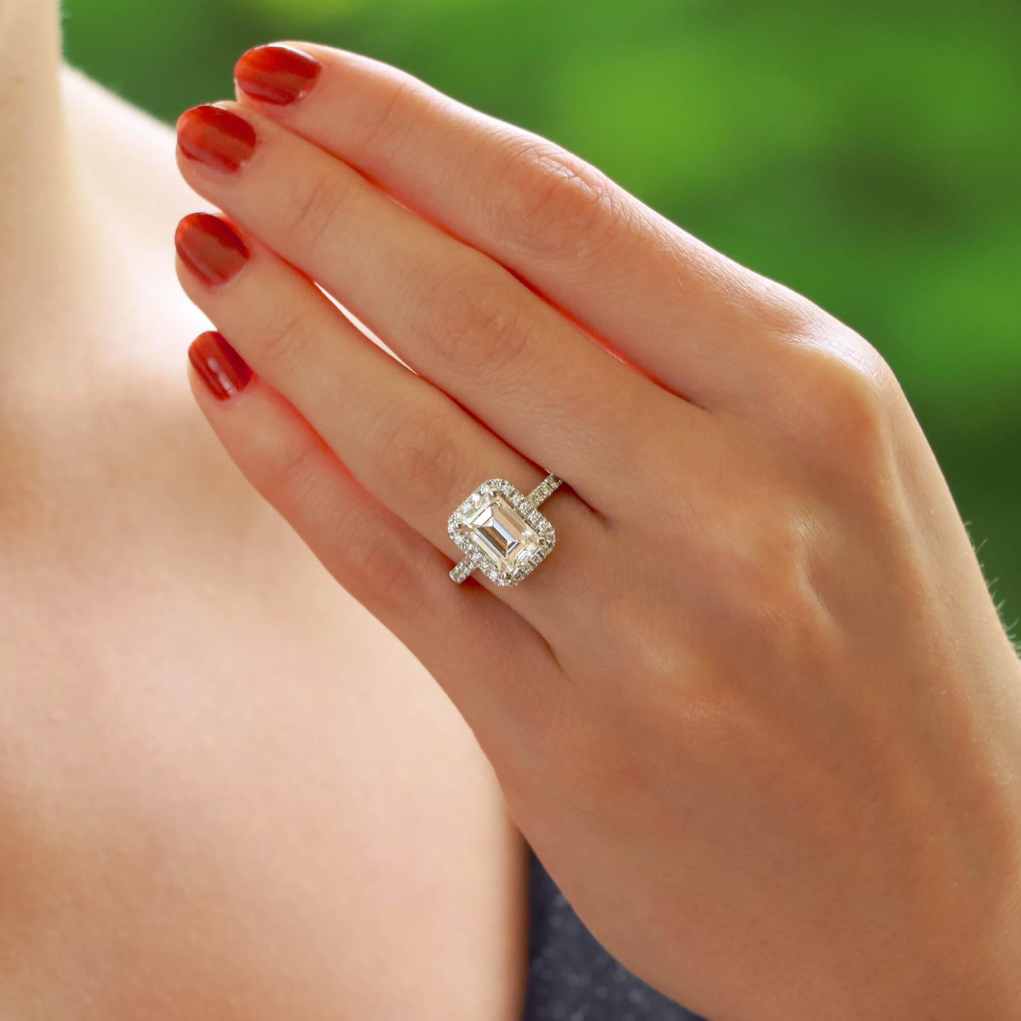 emerald cut halo engagement rings on finger
