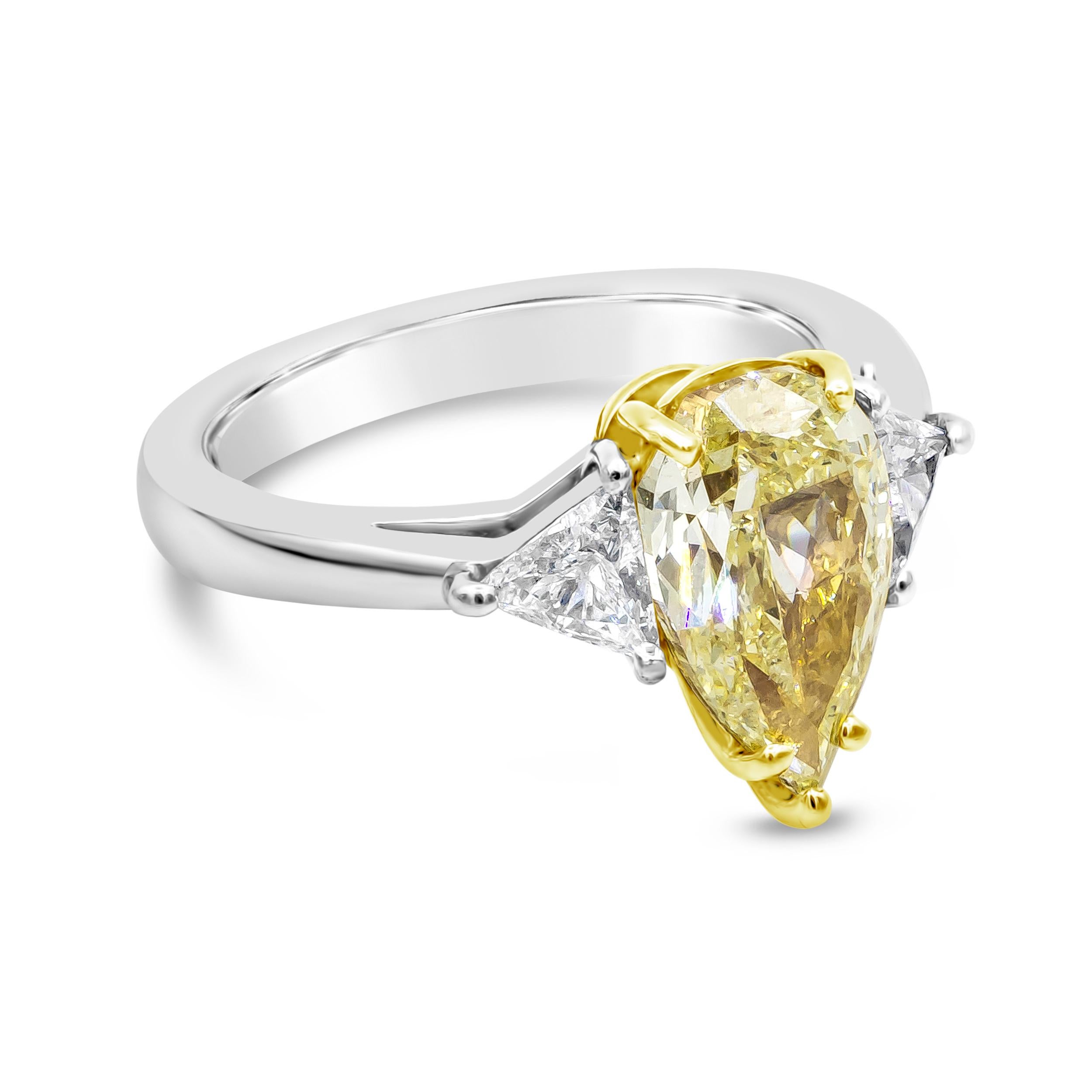Showcasing a 2.45 carat natural pear shape yellow diamond flanked by a brilliant trillion diamond on either side. Accent diamonds weigh 0.47 carats. Set in a polished platinum mounting. GIA certified the center diamond as fancy light yellow in
