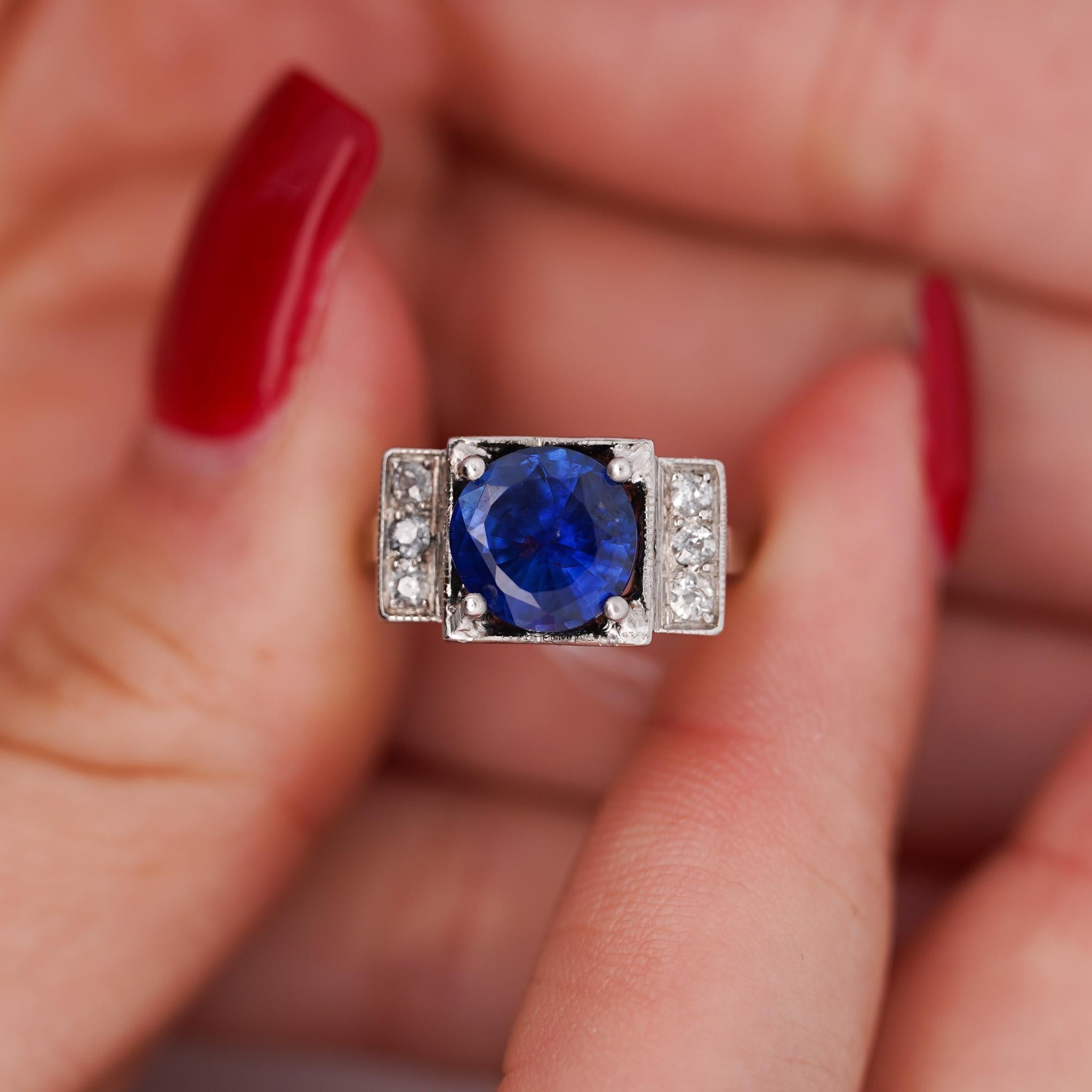 Bague de fiançailles Vintage Art of Vintage saphir et diamant, sertie en platine 900. Une face de bague avec 6 diamants naturels de taille ronde pour former un rectangle. Une monture large qui s'impose sur le doigt.

Le saphir présente une richesse