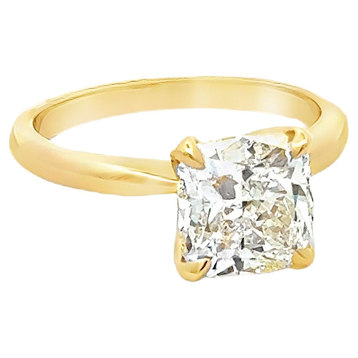 Un classico anello di fidanzamento con solitario, che presenta un diamante taglio cuscino da 2,50 carati certificato da GIA con colore M e purezza SI2, incastonato in una montatura a quattro punte finemente realizzata in oro giallo 18 carati. Taglia