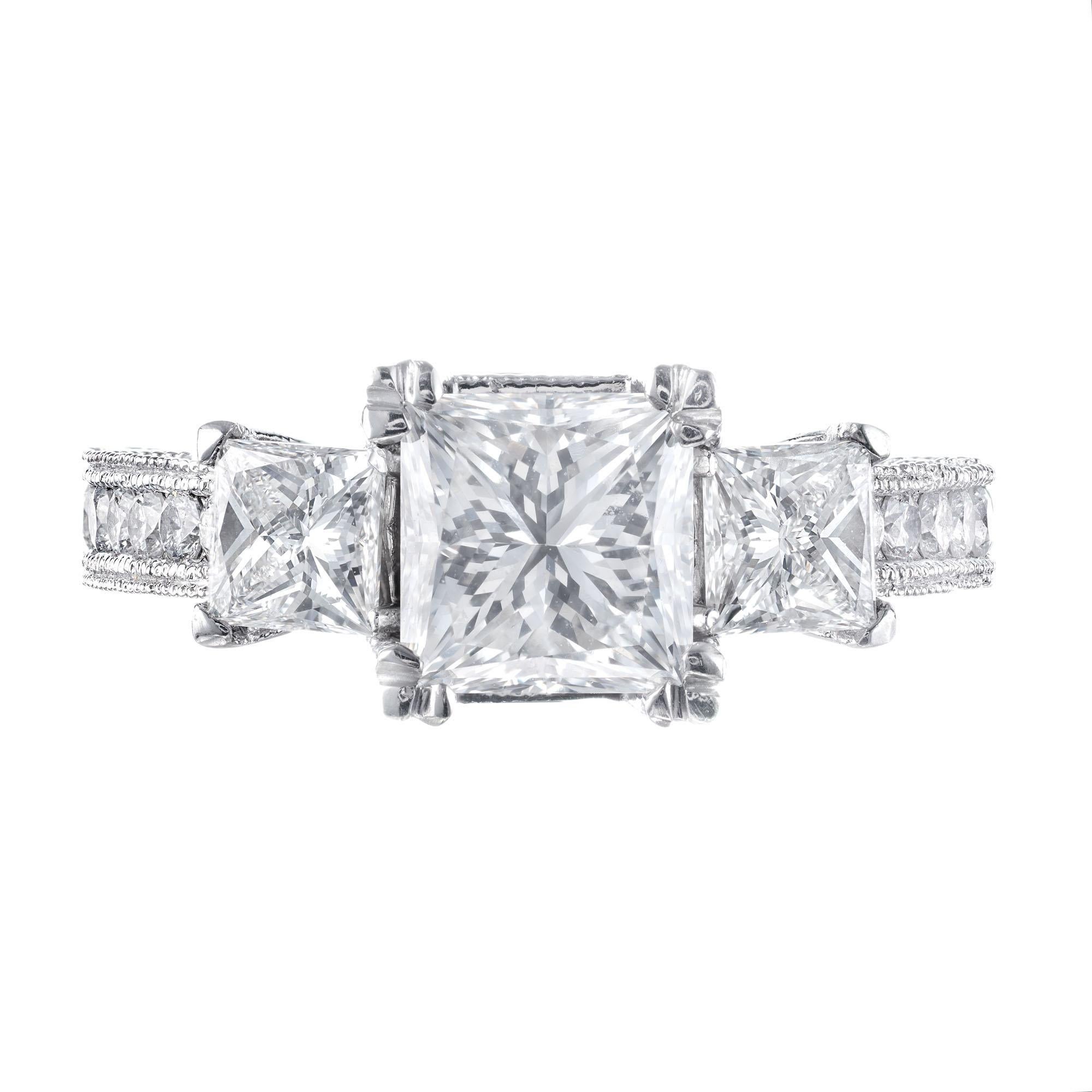 Three-stone diamond engagement ring. Square cut GIA certified center stone with two square cut accent diamonds accented with 32 round brilliant cut diamonds in a Platinum, three-stone bead setting. 

1 square modified brilliant cut diamond, G VVS2