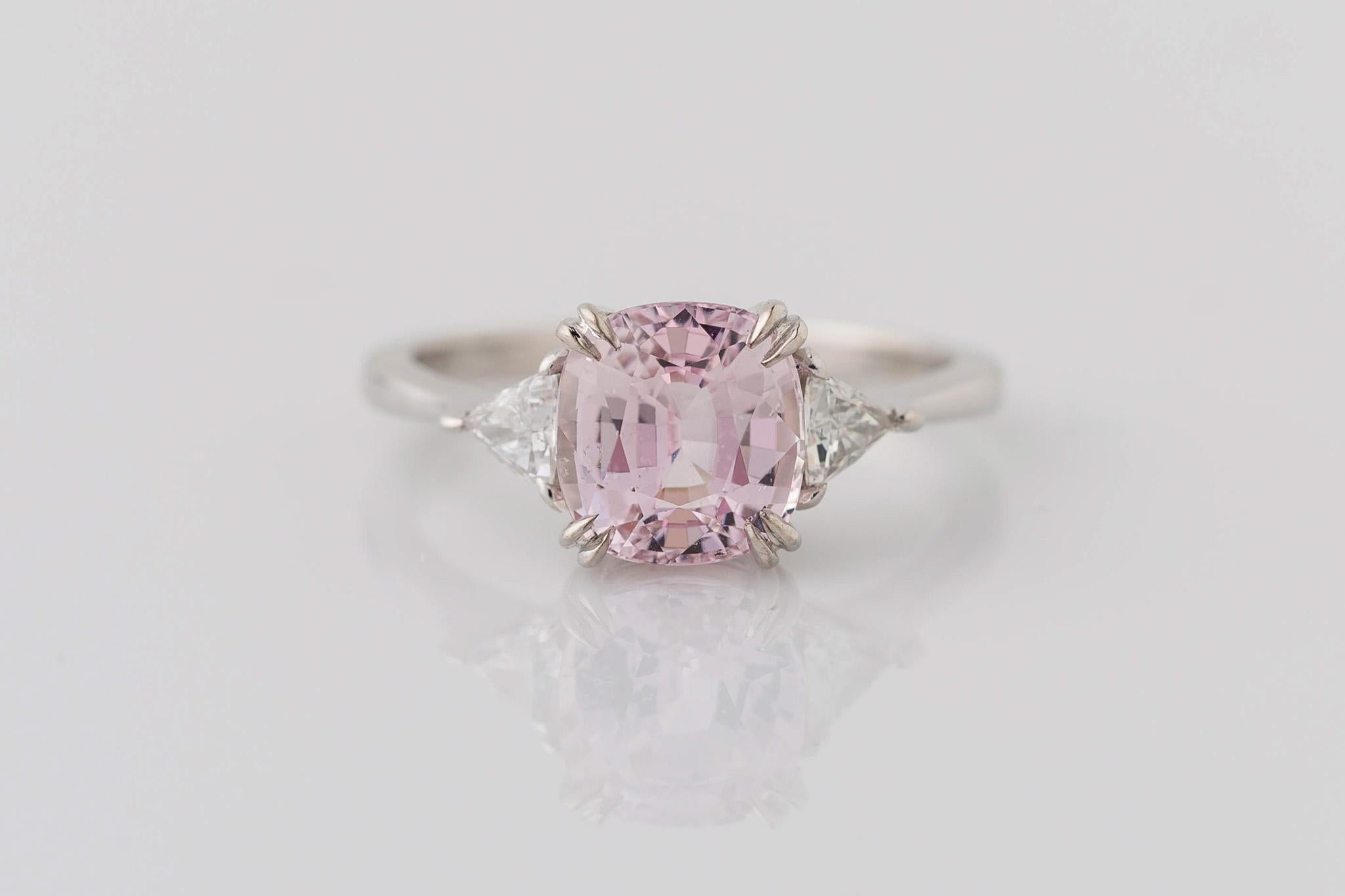 Celebrate your love with our stunning 14K White Gold 3-Stone GIA Certified Cushion Cut Pink Sapphire Ring, complete with Trillion Cut Diamonds. The centerpiece features a mesmerizing 2.59 carat GIA certified unheated pink sapphire, measuring