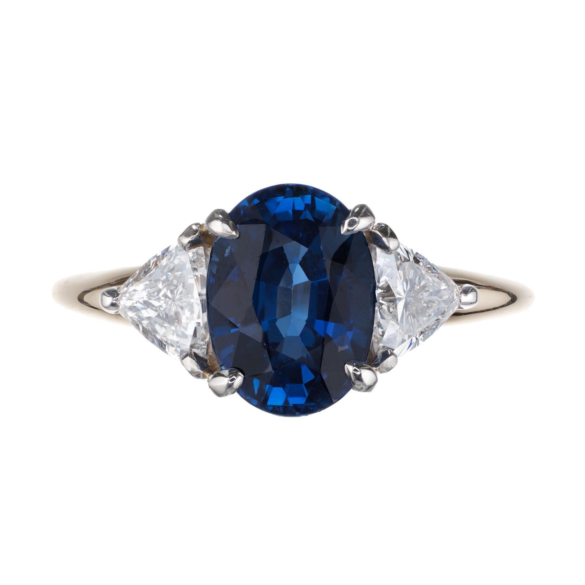 Oval sapphire and diamond engagement ring. GIA certified sapphire in an 18k yellow three-stone setting with two trilliant accent diamonds.  GIA certified.  

1 oval cut blue sapphire SI, approx. 2.62cts GIA certificate # 2205572231
2 trilliant cut