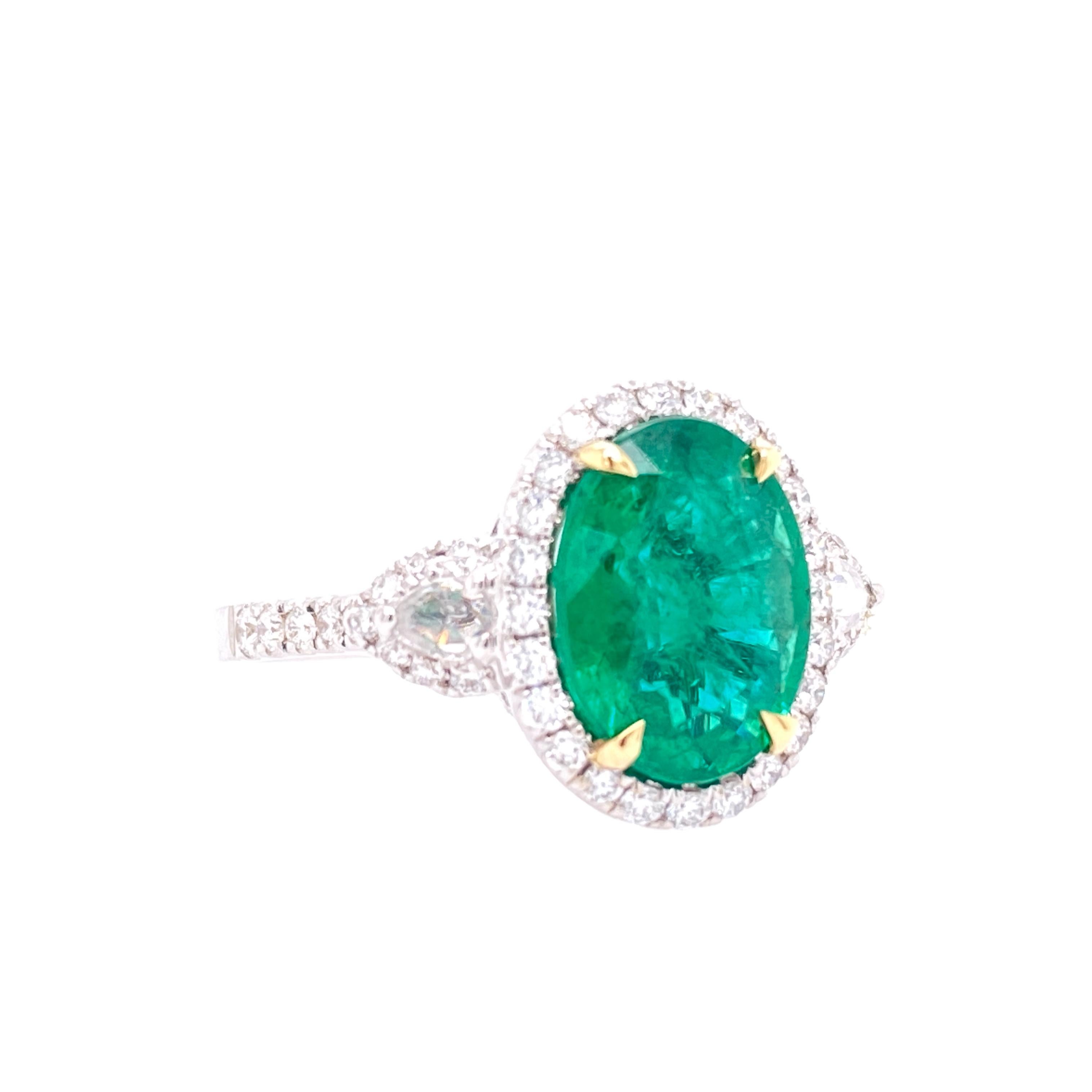 This stunning Cocktail Ring features a beautiful GIA Certified 2.72 Carat Oval African Emerald with a Diamond Halo, that sits on a Diamond Shank. The Emerald is flanked by two Rose Cut White Diamond Side Stones. This Ring is set in 18K White Gold,