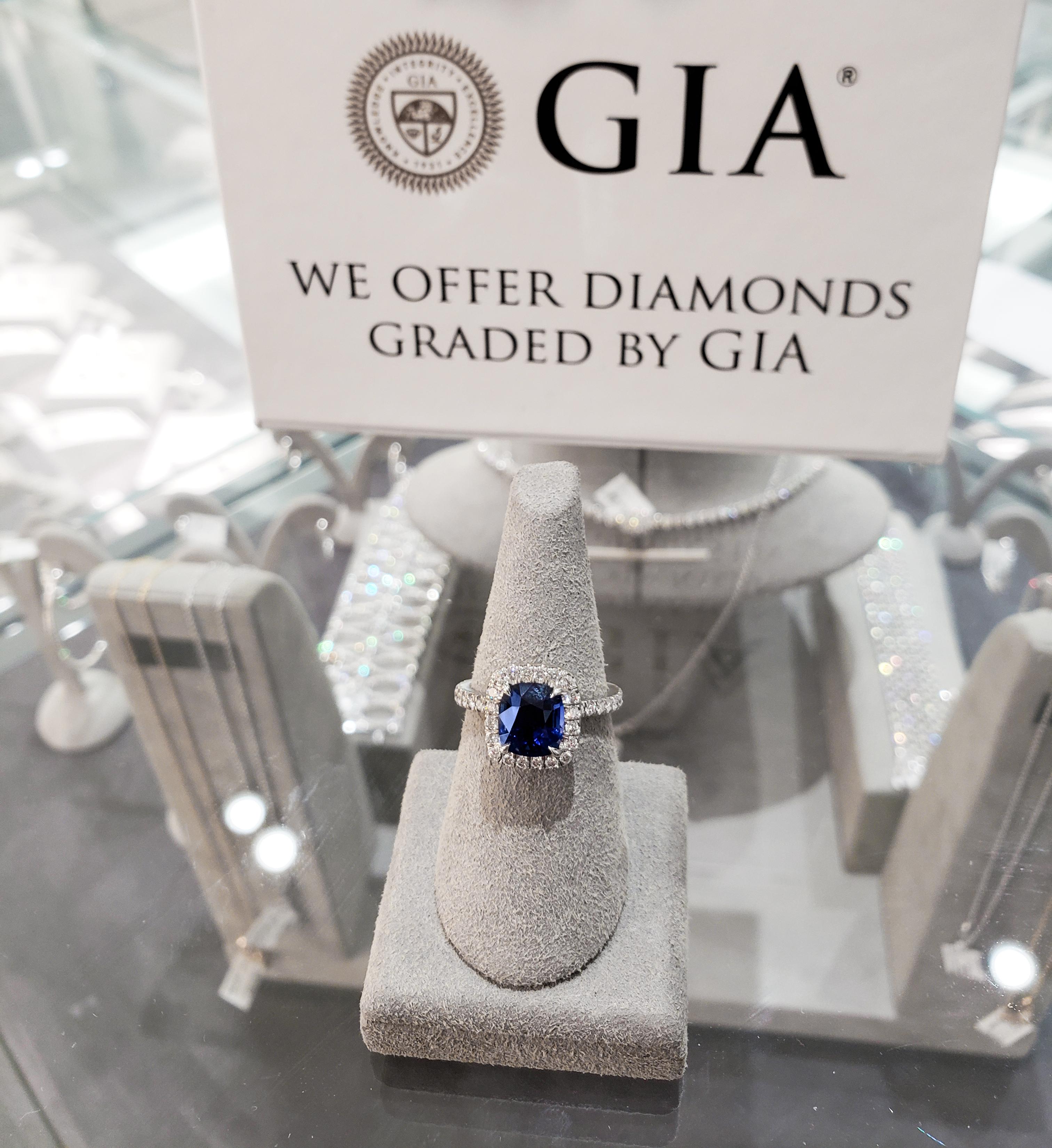This is an incredibly gorgeous and color-rich engagement ring showcasing a 2.75 carat cushion cut sapphire that GIA certified as BLUE in color with no indications of heat treatment. The center stone is surrounded by a single row of sparkling round