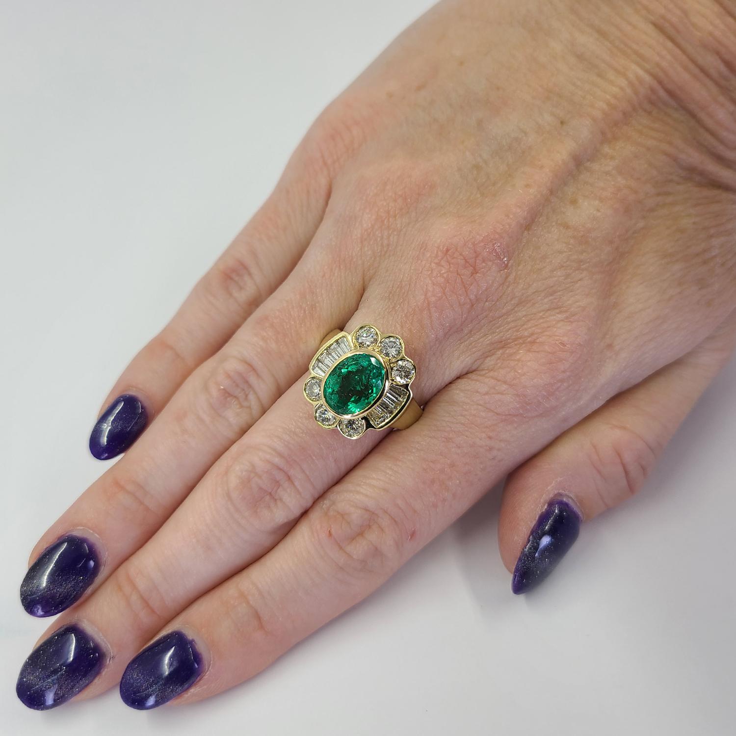 Stunning 18 Karat Yellow Gold Ring Featuring A Bezel Set 2.76 Carat Oval Cut Colombian Emerald (GIA Report #2221713611) Accented By 14 Round and Tapered Baguette Cut Diamonds of VS/SI Clarity and G/H Color Totaling 1.76 Carats. Finger Size 8;