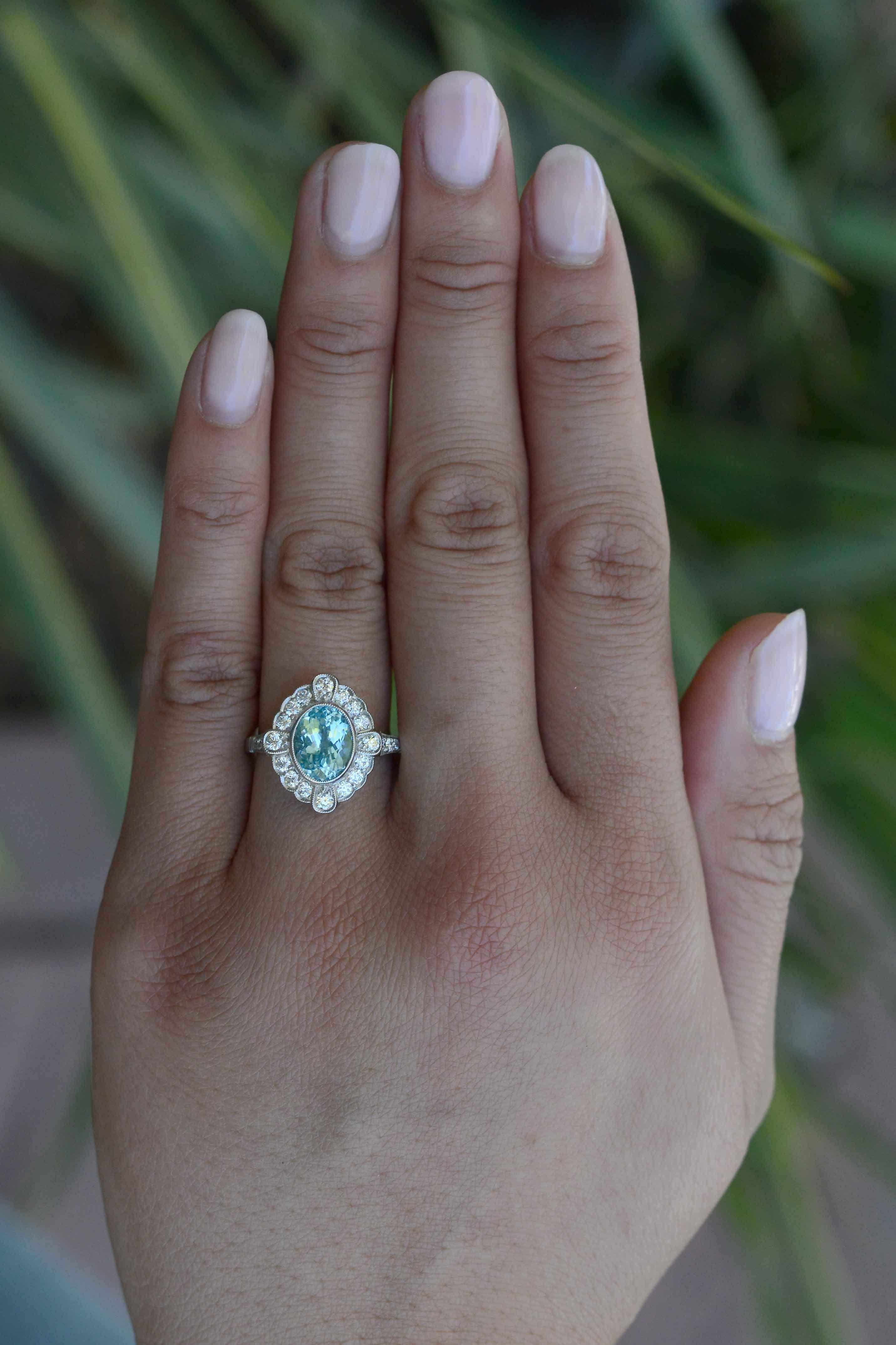 This gemstone engagement ring is truly irresistible. Showing off a mesmerizing Paraiba tourmaline with an incredible Caribbean blue neon color and luster. Surrounding the milgrained, oval setting are 22 glittering diamonds that make the ring bright