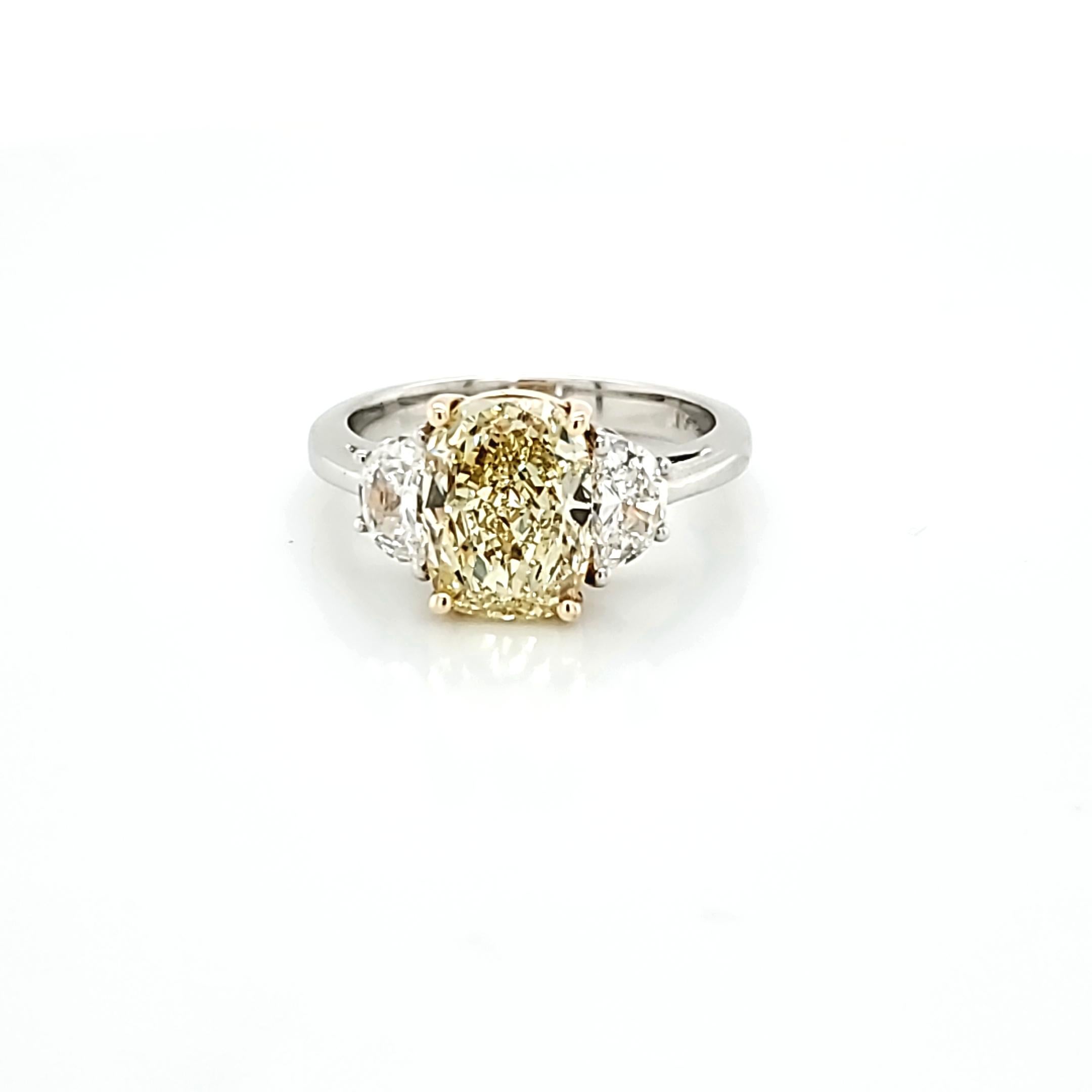 Center stone is a 2.80 carat cushion cut diamond. Fancy Yellow in color and VS1 in clarity. The 2 half moon shaped diamonds weigh 0.73 carats total and are E color and VS2 clarity. Set in a platinum and 18k yellow gold ring. Finger size is currently