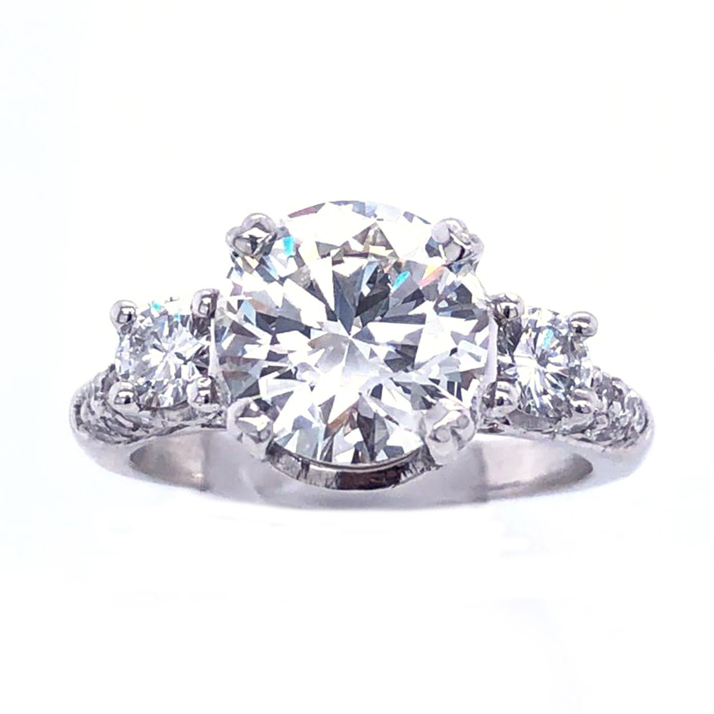 Classic Pave Platinum Diamond ring 2.9 Carat center Round Brilliant Certified by Gia as J - Color , Vs1 Clarity, Excellent - Cut , Very Good - Polish , Very Good - Symmetry and accented by two round diamonds on the side and pave Round Diamonds  ,