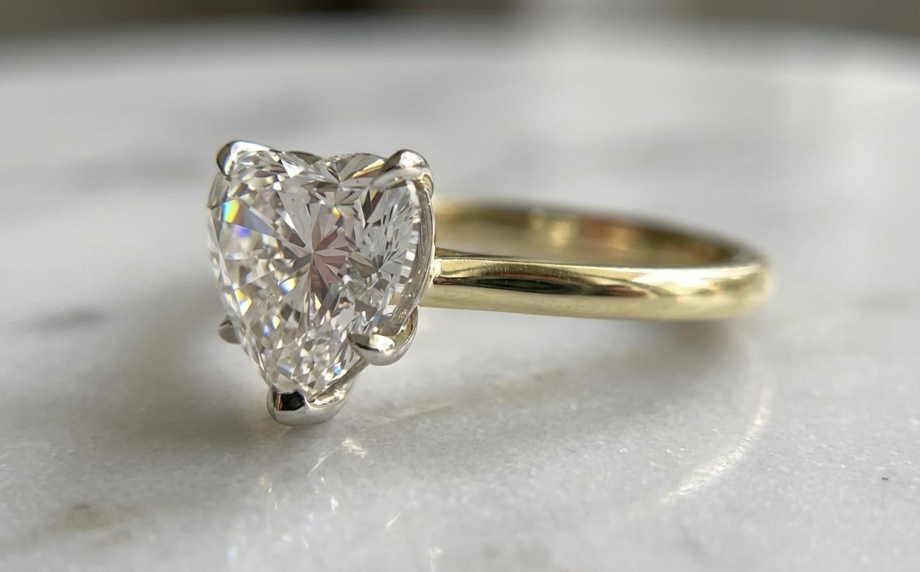 Dieser exquisite Ring präsentiert einen GIA-zertifizierten 3-Karat-Diamanten in Herzform, Farbe F, in einem zweifarbigen Design aus Platin und 18 Karat Gelbgold.

Der Diamant zeigt eine außergewöhnliche Brillanz dank seiner wunderbar ausgewogenen