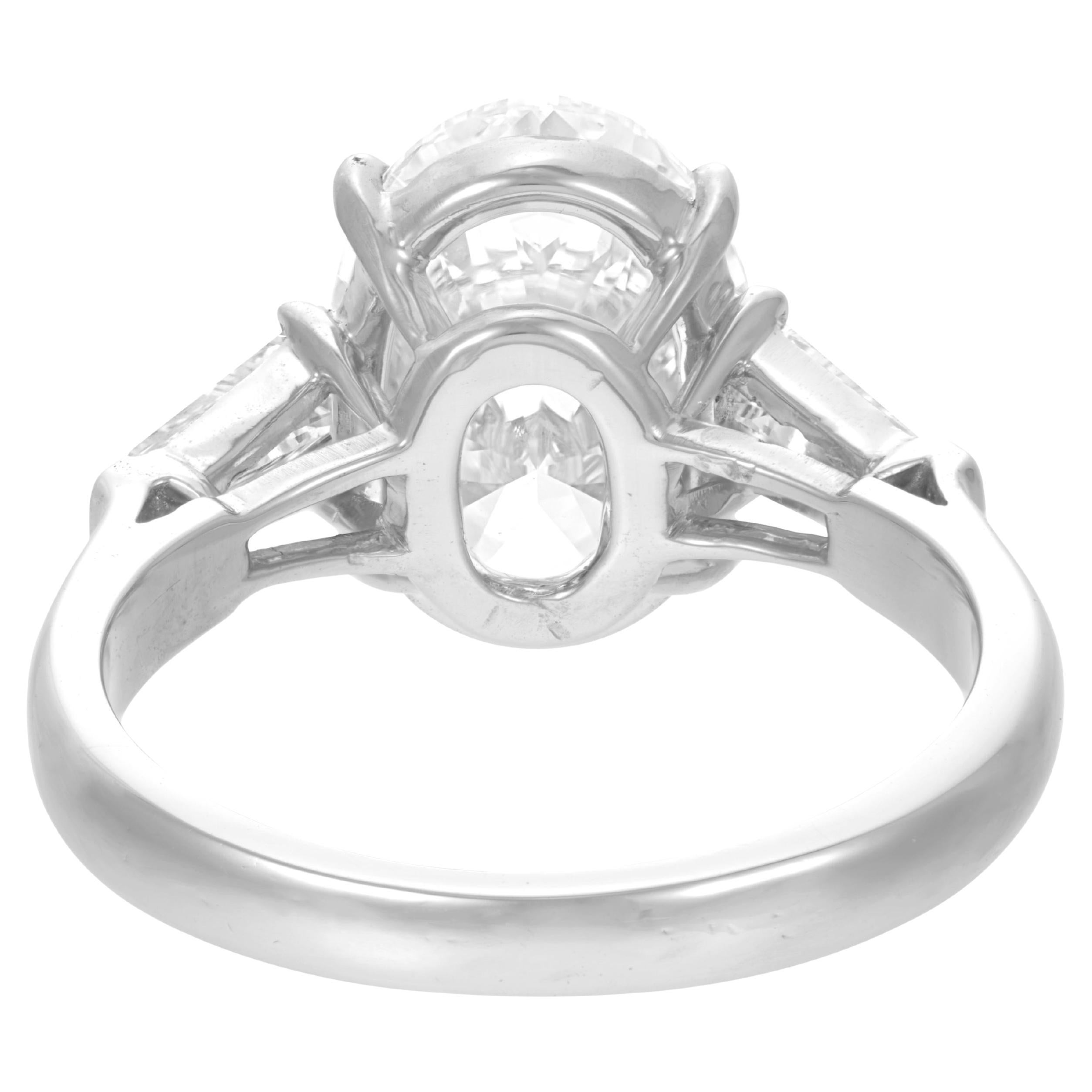 This exquisite engagement ring showcases a 3.05 carat oval-cut diamond, GIA certified and chosen for its rare combination of grace and purity. The elongated shape of the center stone offers a refined silhouette that flatters the finger while