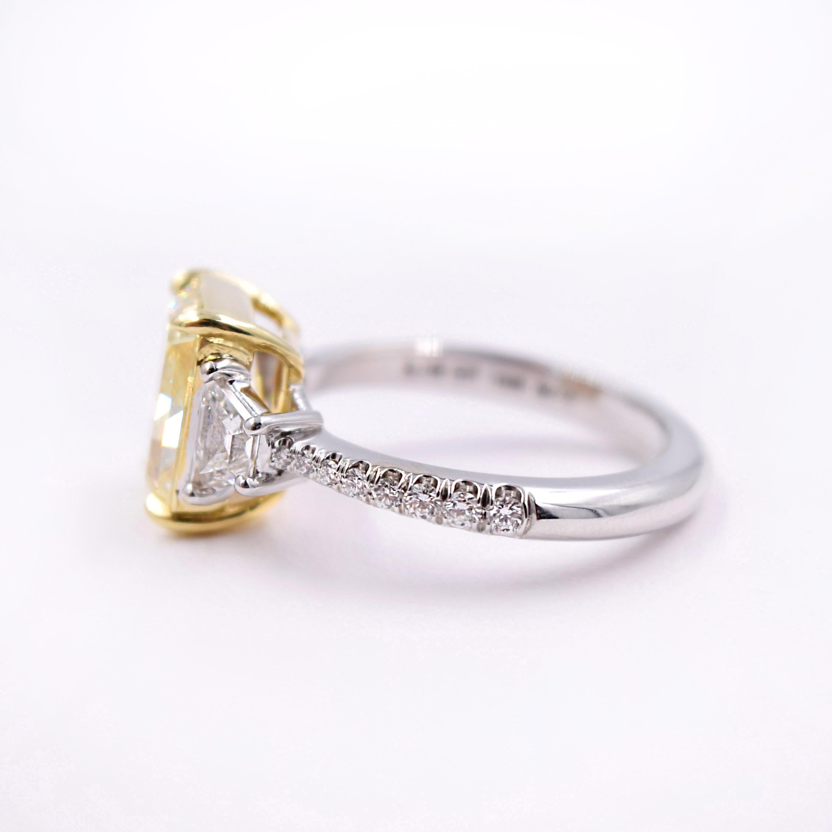 Novel Collection Diamond Ring:
GIA certified #1182709866
18K White and Yellow Gold, 4.82 grams
Radiant cut fancy yellow center diamond VVS1 clarity 3.15cts
2 Trapezoid cut white diamonds F color VS clarity 0.58cts
16 brilliant cut white diamonds