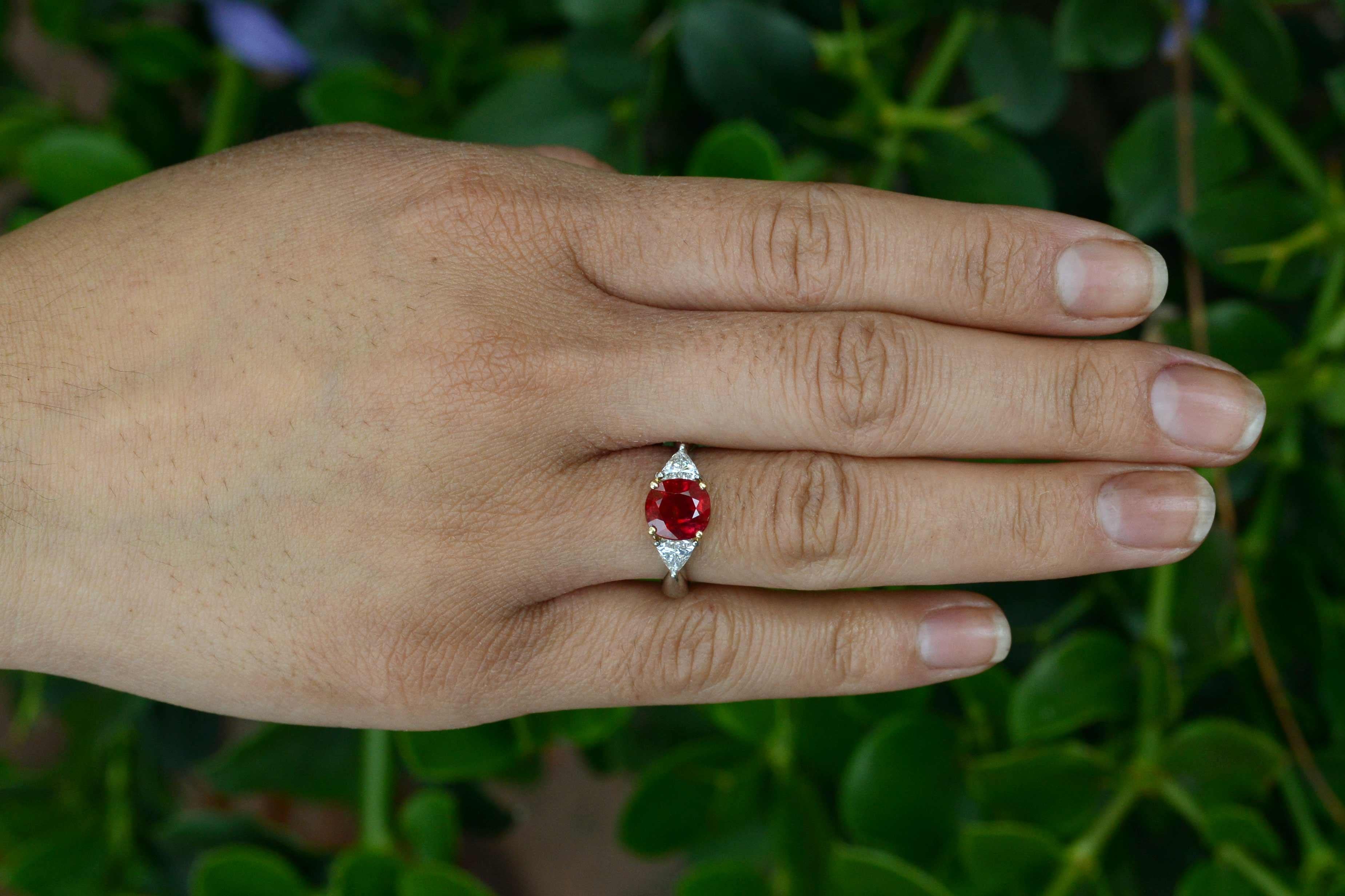 Boasting a rare, 3 carat GIA certified Pigeon Blood Red Burma Ruby commands center stage, accompanied by a pair of fiery, sparkling triangle diamonds, this 3 stone stunner is a real show-stopper. The vivid color of Burmese rubies is prized among